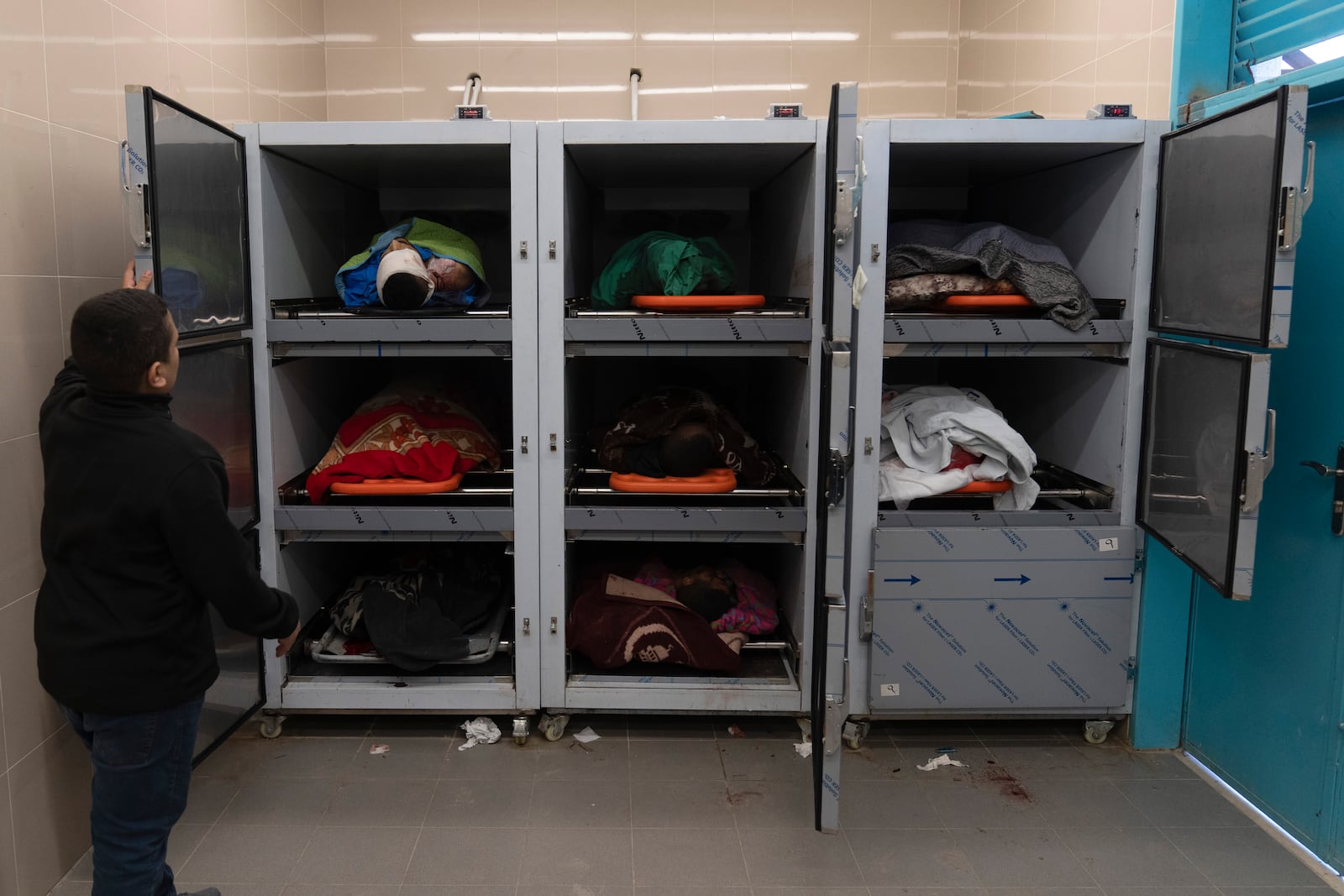 A youth looks at the bodies of Palestinians at the hospital morgue after they were killed during a military operation in the Tulkarem refugee camp near the West Bank city of Tulkarem, Wednesday, Dec. 25, 2024. (AP Photo/Majdi Mohammed)