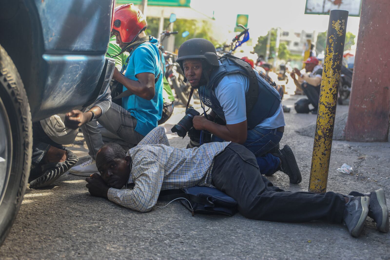 Journalists take cover from the exchange of gunfire between gangs and police in Port-au-Prince, Haiti, Monday, Nov. 11, 2024. (AP Photo/Odelyn Joseph)