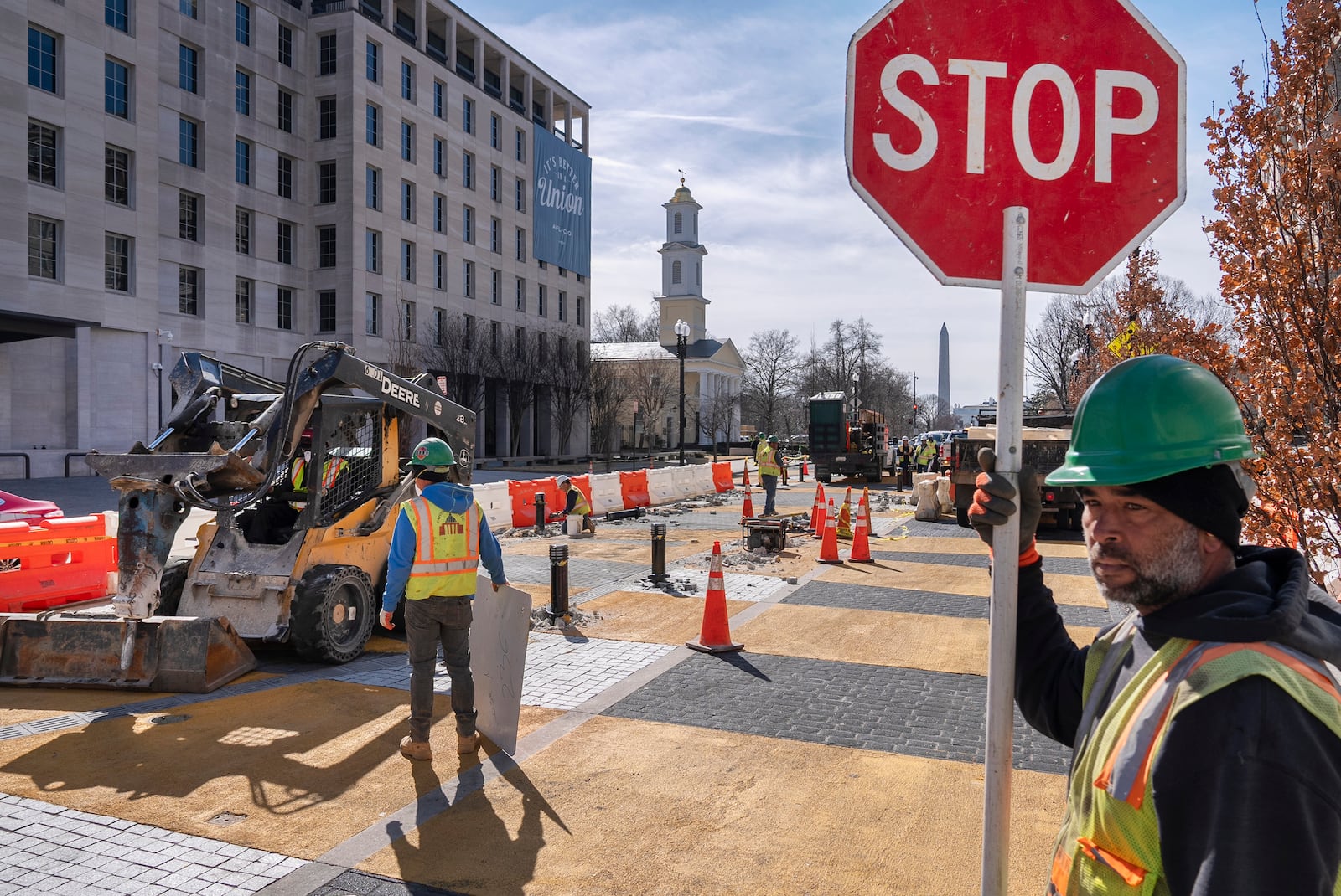 With the White House and Washington Monument in the background, a worker holds a traffic stop sign as demolition begins on the Black Lives Matter mural, Monday, March 10, 2025, in Washington. (AP Photo/Jacquelyn Martin)