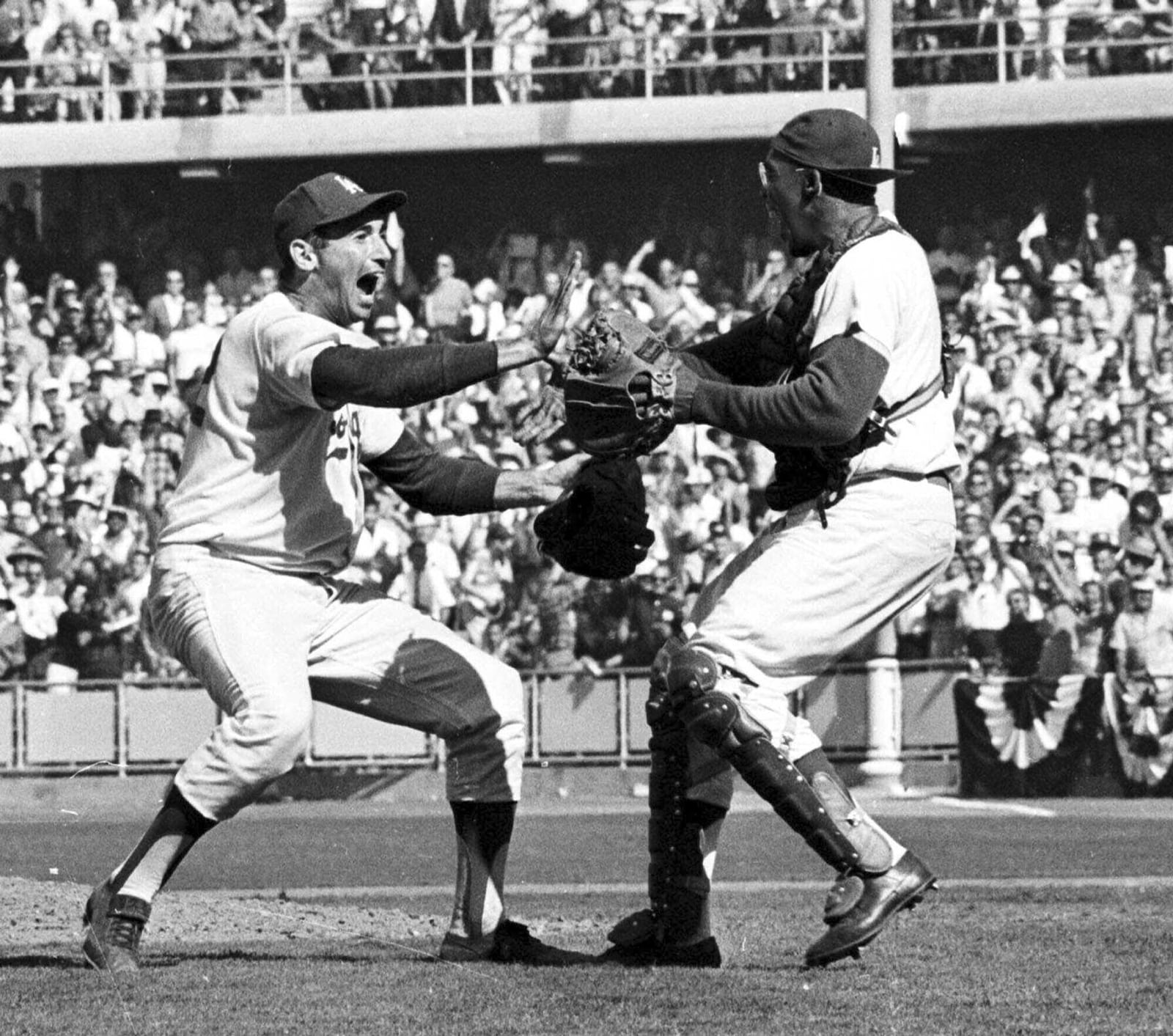 Pitcher Sandy Koufax, left, and catcher John Roseboro celebrate on the field in Los Angeles, Ca., Oct. 6,1963, after the Los Angeles Dodgers beat the New York Yankees 2-1 to take the 1963 World Series in four straight games. (AP Photo/File)