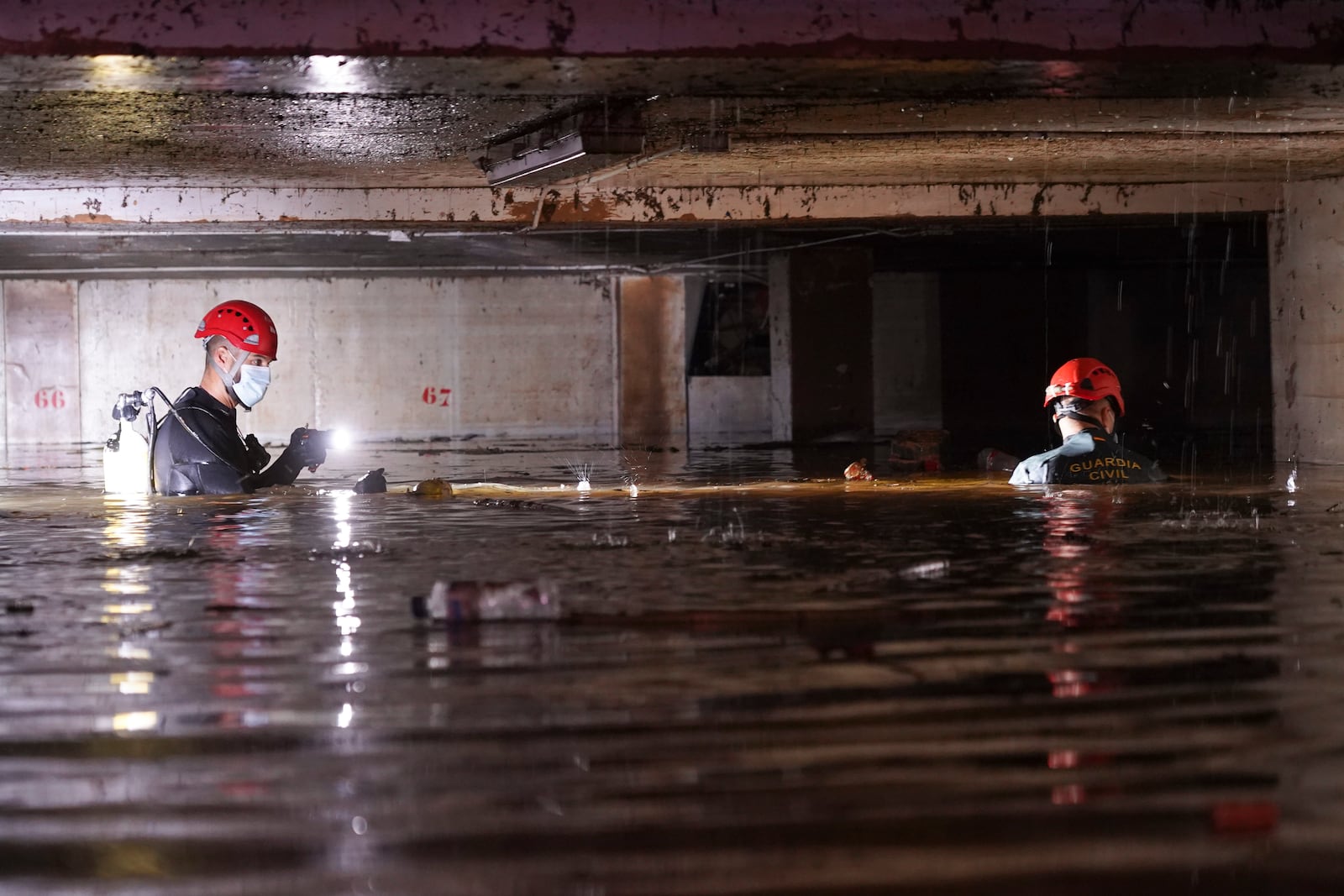 Civil Guards walk in a flooded indoor car park to check cars for bodies after floods in Paiporta, near Valencia, Spain, Monday, Nov. 4, 2024. (AP Photo/Alberto Saiz)