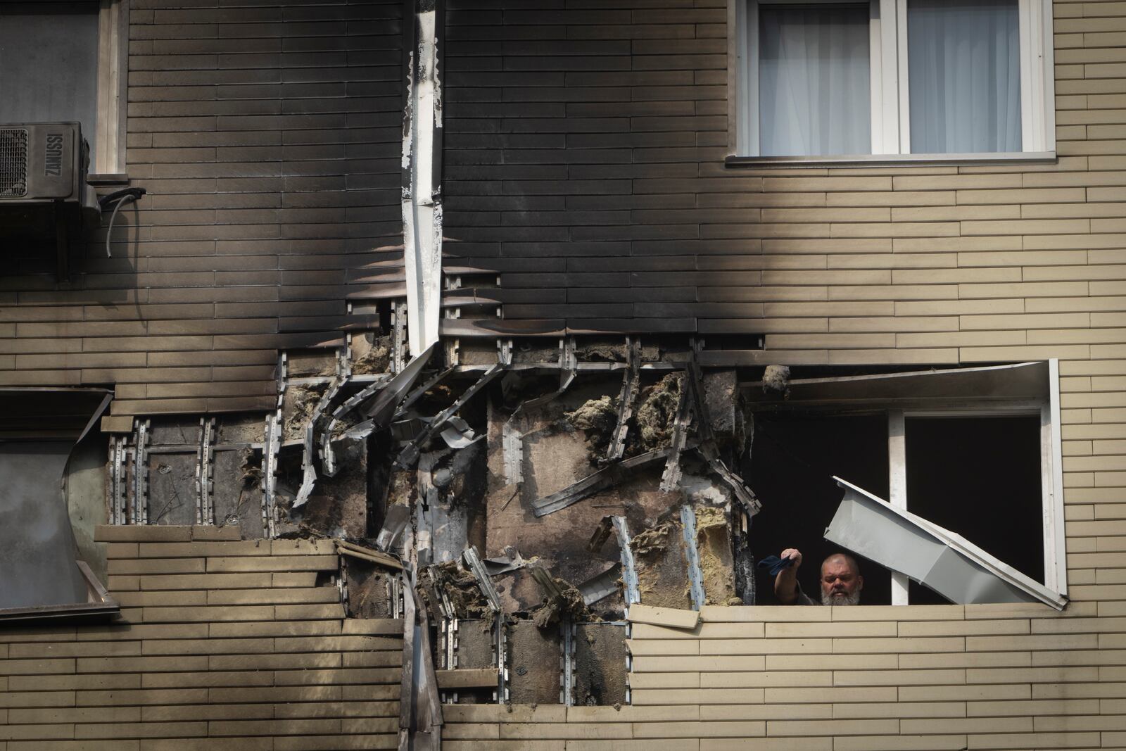 A resident cleans up the damaged apartment in a multi-storey house after a Russia's night drone attack in Kyiv, Ukraine, Sunday, March 23, 2025. (AP Photo/Efrem Lukatsky)