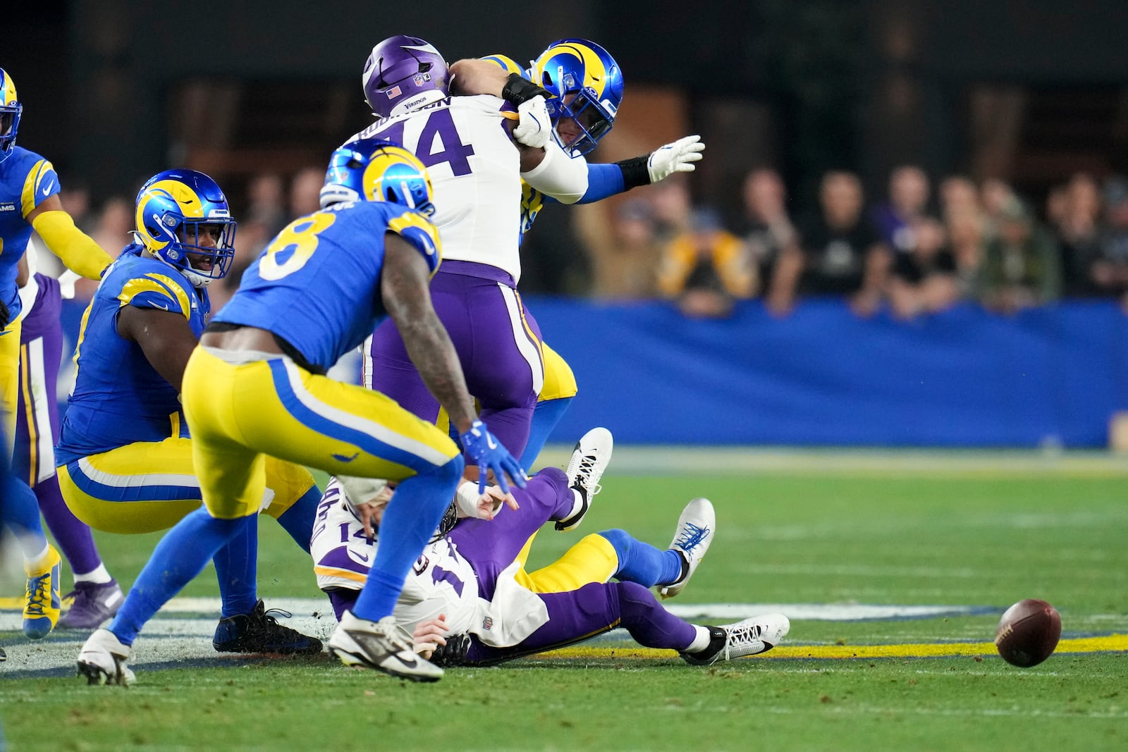 Los Angeles Rams linebacker Jared Verse (8) looks to pick up a Minnesota Vikings quarterback Sam Darnold (14) fumble caused by Ahkello Witherspoon (4) during the first half of an NFL wild card playoff football game, Monday, Jan. 13, 2025, in Glendale, Ariz.Verse returned the fumble for a 57-yard touchdown. (AP Photo/Ross D. Franklin)