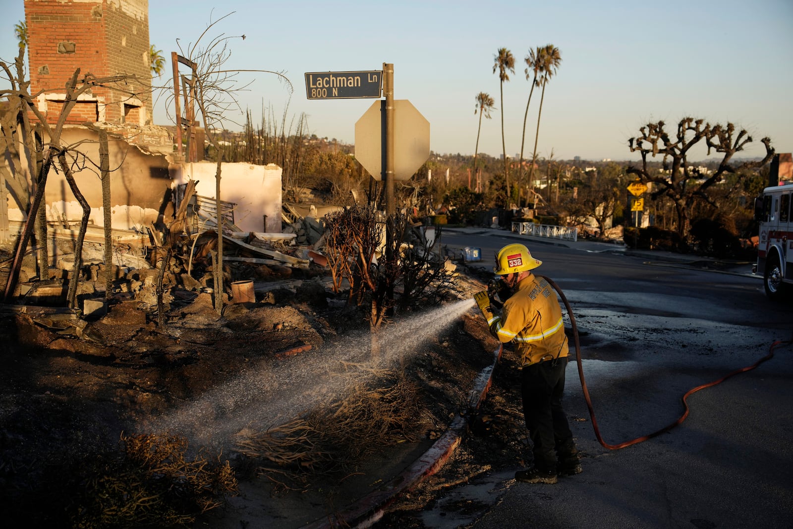 James Lyons, an engineer with the Apple Valley Fire District, sprays hot spots at a home burned by the Palisades Fire, Monday, Jan. 13, 2025, in Pacific Palisades, Calif. (AP Photo/John Locher)