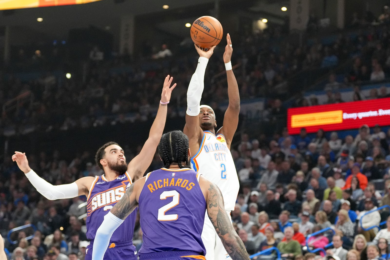 Oklahoma City Thunder guard Shai Gilgeous-Alexander, right, shoots near Phoenix guard Tyus Jones, left, and center Nick Richards, middle, during the first half of an NBA basketball game, Wednesday, Feb. 5, 2025, in Oklahoma City. (AP Photo/Kyle Phillips)