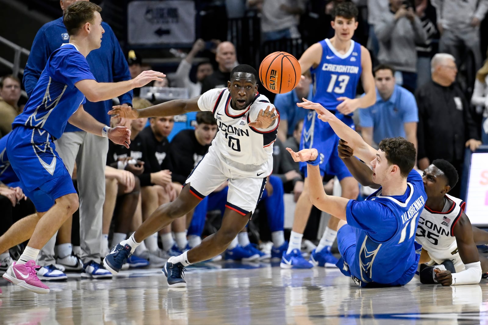 Creighton center Ryan Kalkbrenner (11) passes to guard Steven Ashworth, left, as UConn guard Hassan Diarra, center, and center Samson Johnson, right, defend in the second half of an NCAA college basketball game, Saturday, Jan. 18, 2025, in Storrs, Conn. (AP Photo/Jessica Hill)