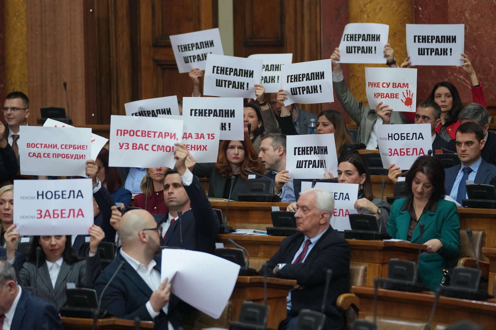 Opposition lawmakers hold banners reading: "General strike!" during a parliament session in Belgrade, Serbia, Tuesday, March 4, 2025. (AP Photo/Darko Vojinovic)