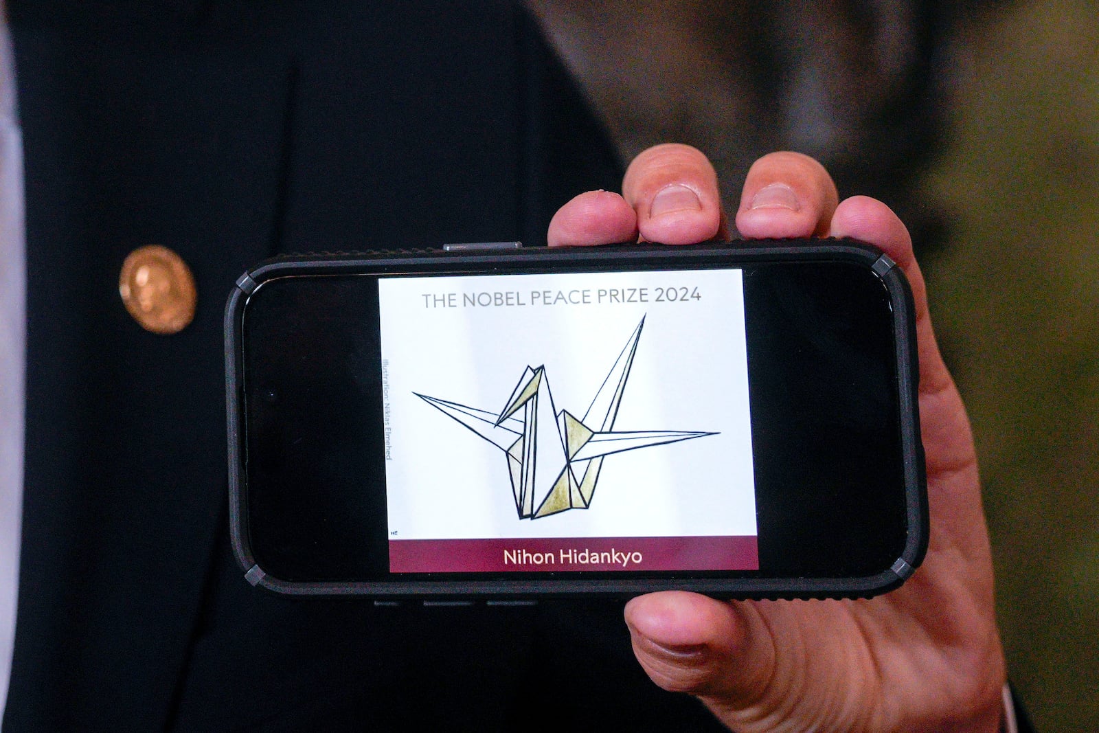 The head of the Nobel Committee, Jorgen Watne Frydnes, shows the logo of the Japanese organization Nihon Hidankyo, the winner of the Nobel Peace Prize for 2024, at the Nobel Institute in Oslo, Norway, Friday, Oct. 11, 2024. The Nobel Peace Prize was awarded Friday to Nihon Hidankyo, a Japanese organization of survivors of the U.S. atomic bombings of Hiroshima and Nagasaki, for its activism against nuclear weapons. (Javad Parsa/NTB Scanpix via AP)