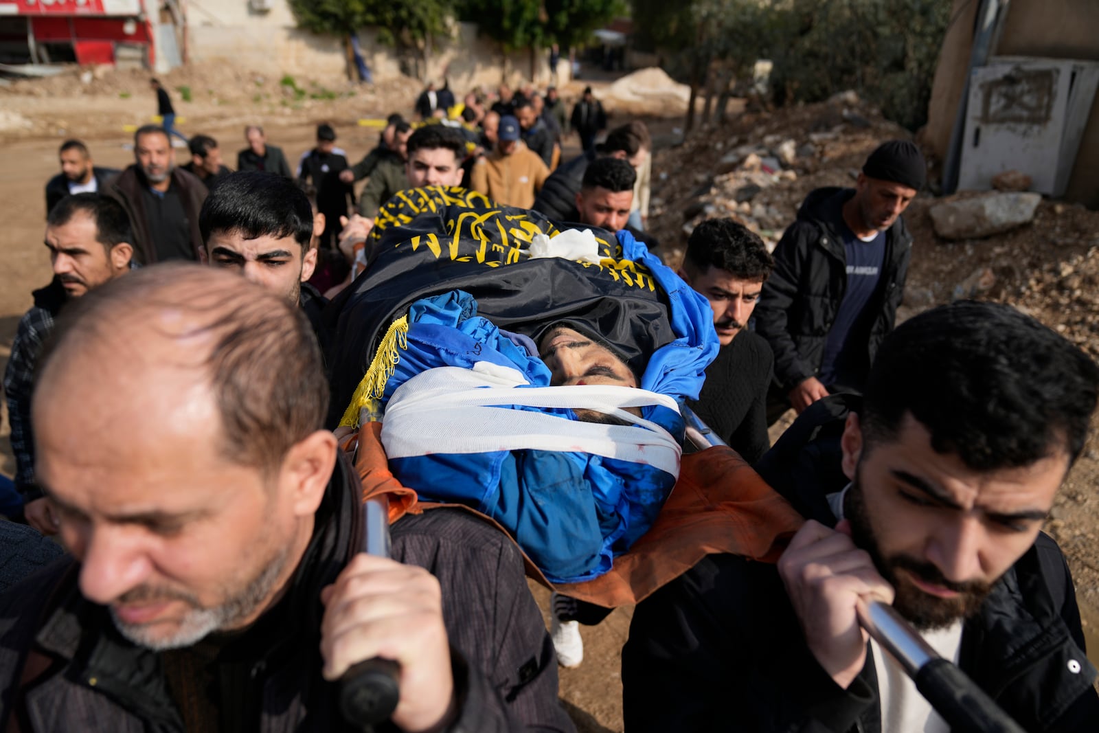 Mourners carry the bodies of six Palestinians who were killed during an Israeli airstrike on Wednesday, wrapped with Islamic Jihad flags, during their funeral in the West Bank refugee camp of Jenin Thursday, Jan. 16, 2025. (AP Photo/Nasser Nasser)