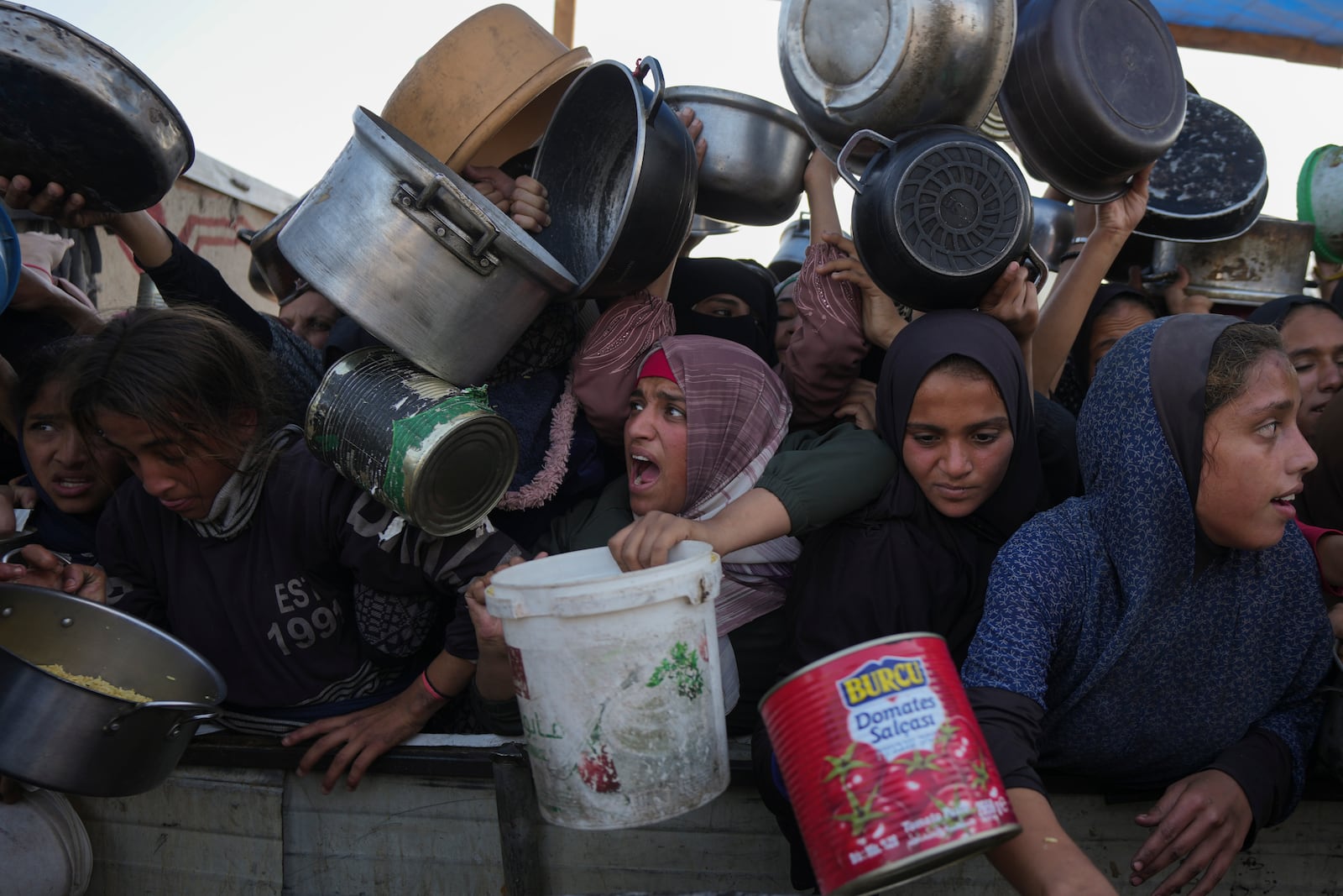 Palestinian women and girls struggle to reach for food at a distribution center in Khan Younis, Gaza Strip Friday, Dec. 6, 2024. (AP Photo/Abdel Kareem Hana)