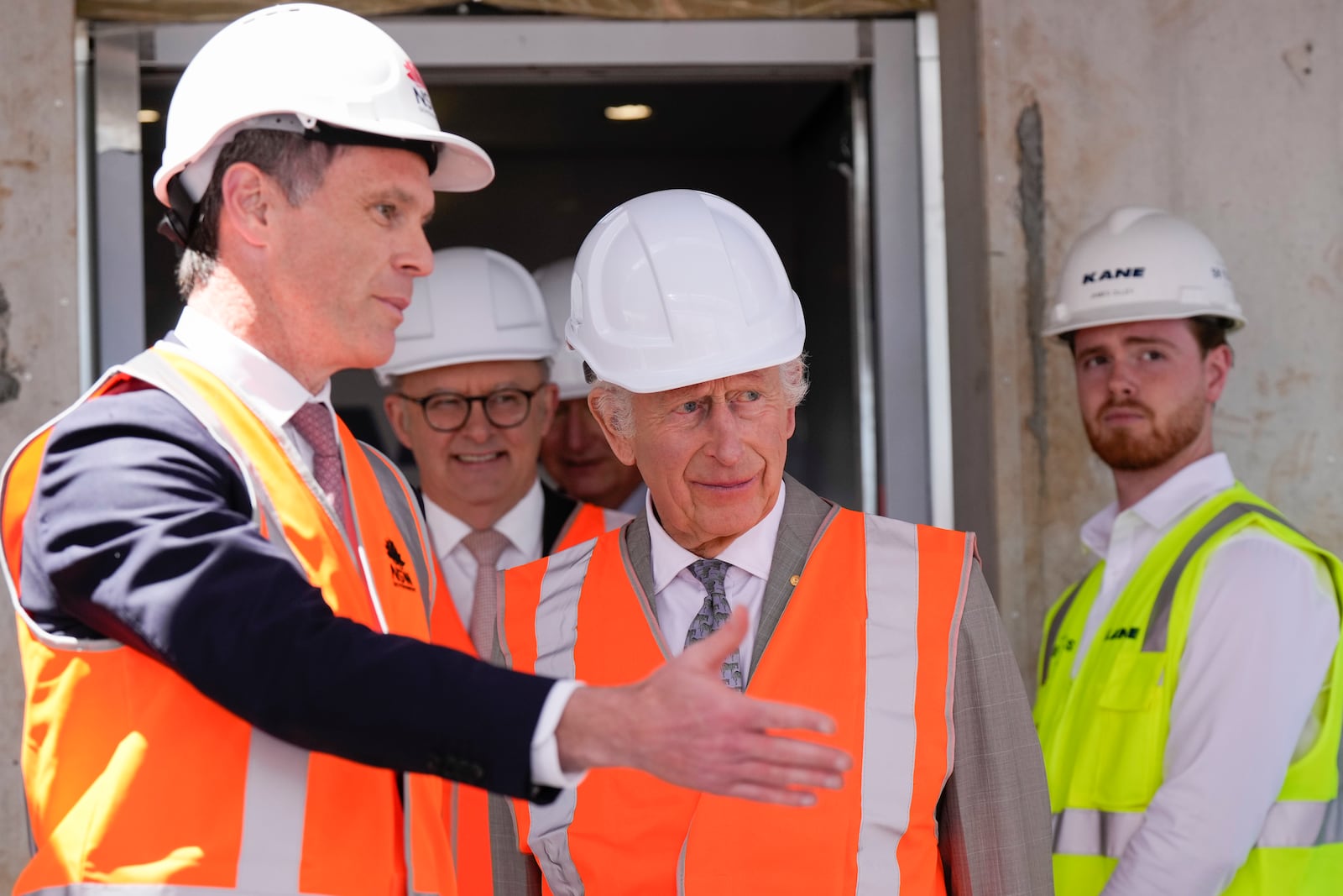 Britain's King Charles III, center, is assisted by Albanese and New South Wales Premier Chris Minns, left, while Australia's Prime Minister Anthony Albanese walks behind as he visits the Homes NSW Cowper Street development in Sydney, Australia, Tuesday, Oct. 22, 2024. (AP Photo/Mark Baker, Pool)