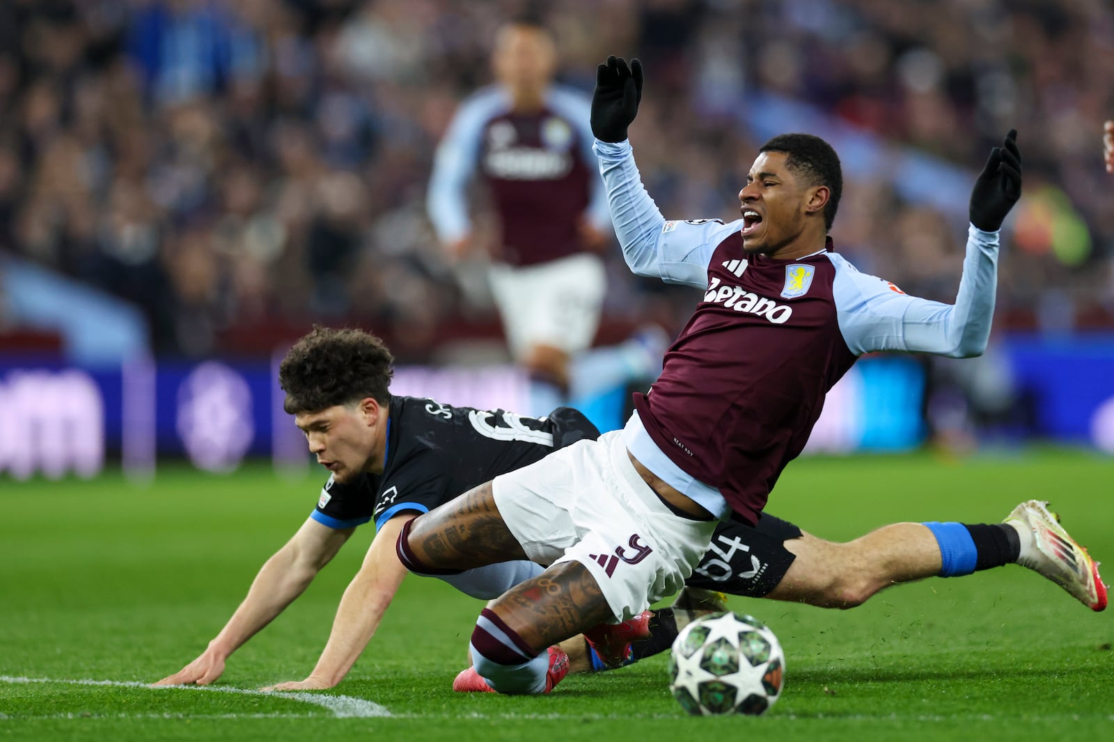 Aston Villa's Marcus Rashford, front, duels for the ball with Brugge's Kyriani Sabbe during the Champions League round of 16 second leg soccer match between Aston Villa and Club Brugge at the Villa Park stadium in Birmingham, England, Wednesday, March 12, 2025. (AP Photo/Darren Staples)