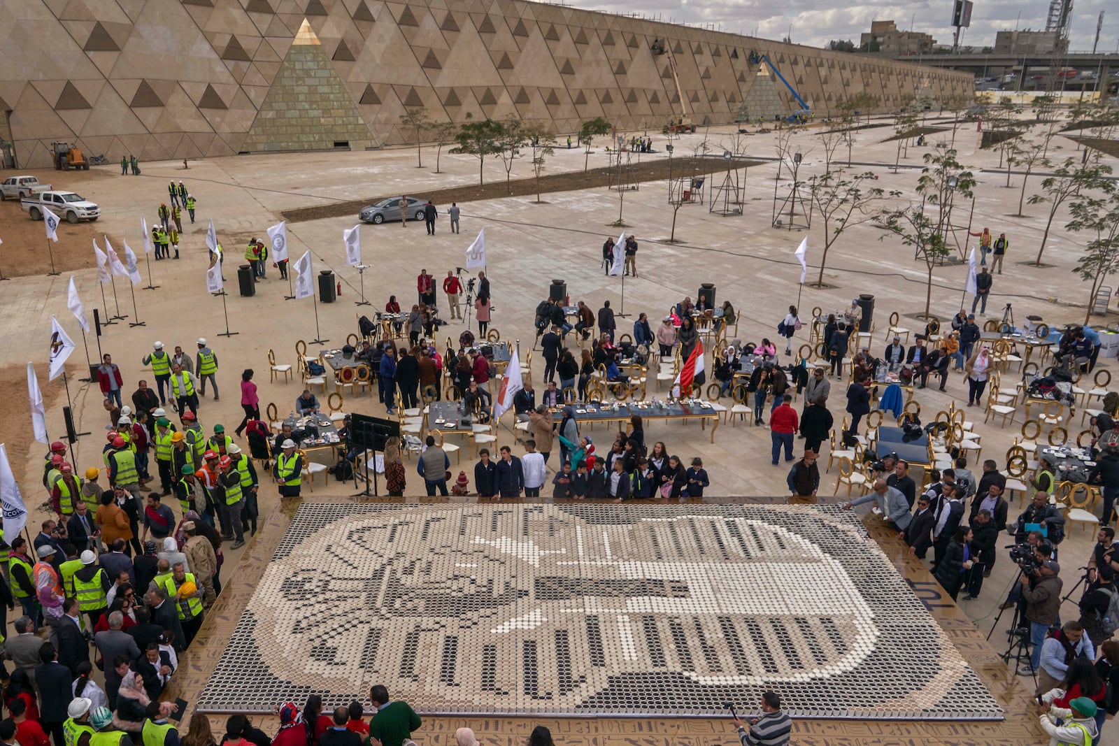 FILE - Visitors walk past the cups used in the mosaic of ancient Egyptian King Tutankhamun's mask at the yard of the Grand Egyptian Museum near the Great Pyramids of Giza, Egypt, Saturday, Dec. 28, 2019. (AP Photo/Hamada Elrasam, File)