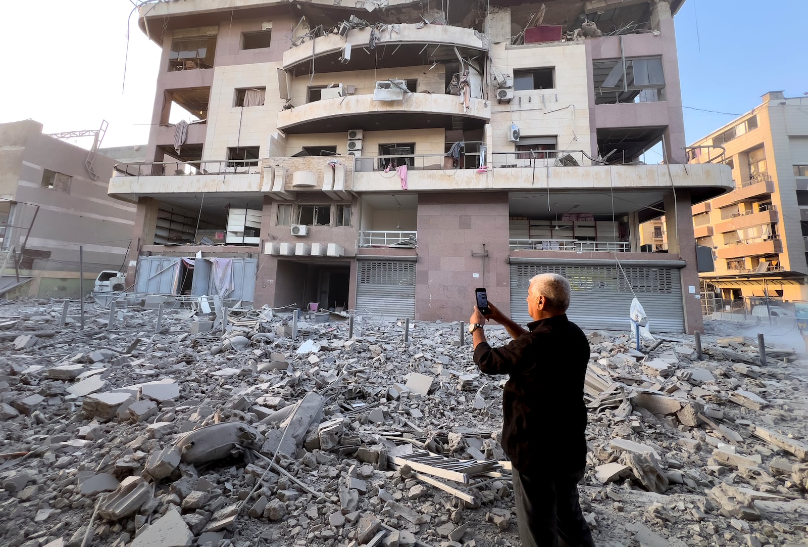 A man takes pictures by his mobile phone of a destroyed building hit by an Israeli airstrike on Dahiyeh, in the southern suburb of Beirut, Lebanon, early Friday, Nov. 1, 2024. (AP Photo/Hussein Malla)