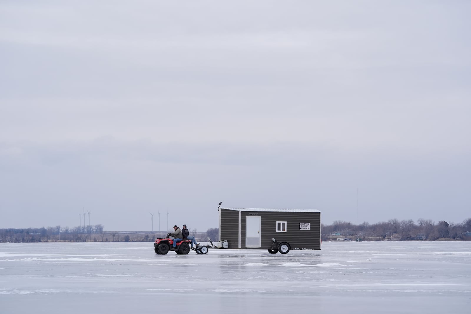 Long-time residents transport an ice fishing shed across the frozen Okabena Lake in Worthington, Minnesota, Saturday, Jan. 11, 2025. (AP Photo/Abbie Parr)