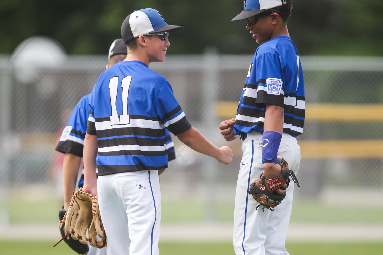 Hamilton West Side third baseman Ethan Mueller (11) shares a moment on the mound with pitcher Braedyn Moore during Thursday’s game against Canfield in the winners’ bracket final of the Ohio Little League 12-year-old baseball tournament at Ford Park in Maumee. CONTRIBUTED PHOTO BY SCOTT GRAU