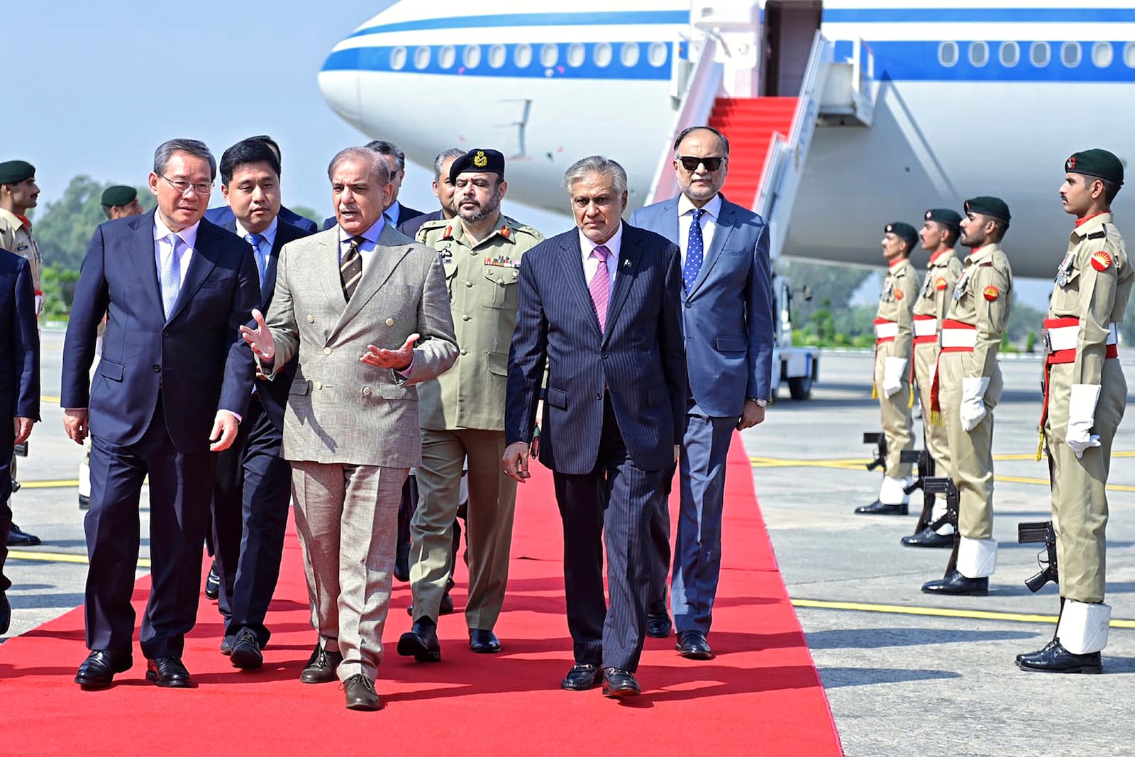 In this photo released by the Press Information Department, China's Premier Li Qiang, left, walks Pakistan's Prime Minister Shehbaz Sharif, second left, upon his arrival at an airbase in Rawalpindi, Pakistan, Monday, Oct. 14, 2024. (Press Information Department via AP)