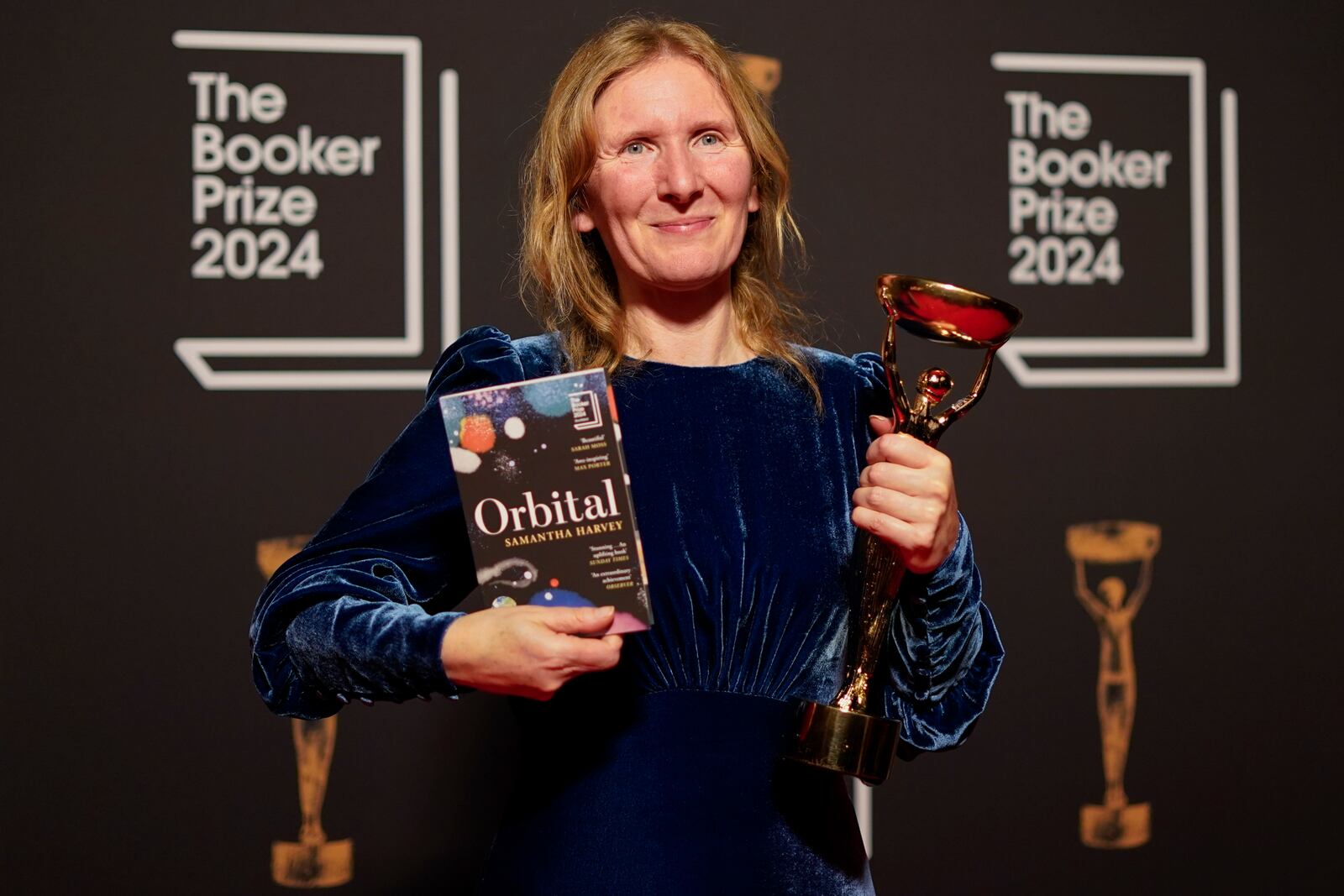 Samantha Harvey poses with the trophy and her book "Orbital" after winning the Booker Prize award 2024, in London, Tuesday, Nov. 12, 2024. (AP Photo/Alberto Pezzali)