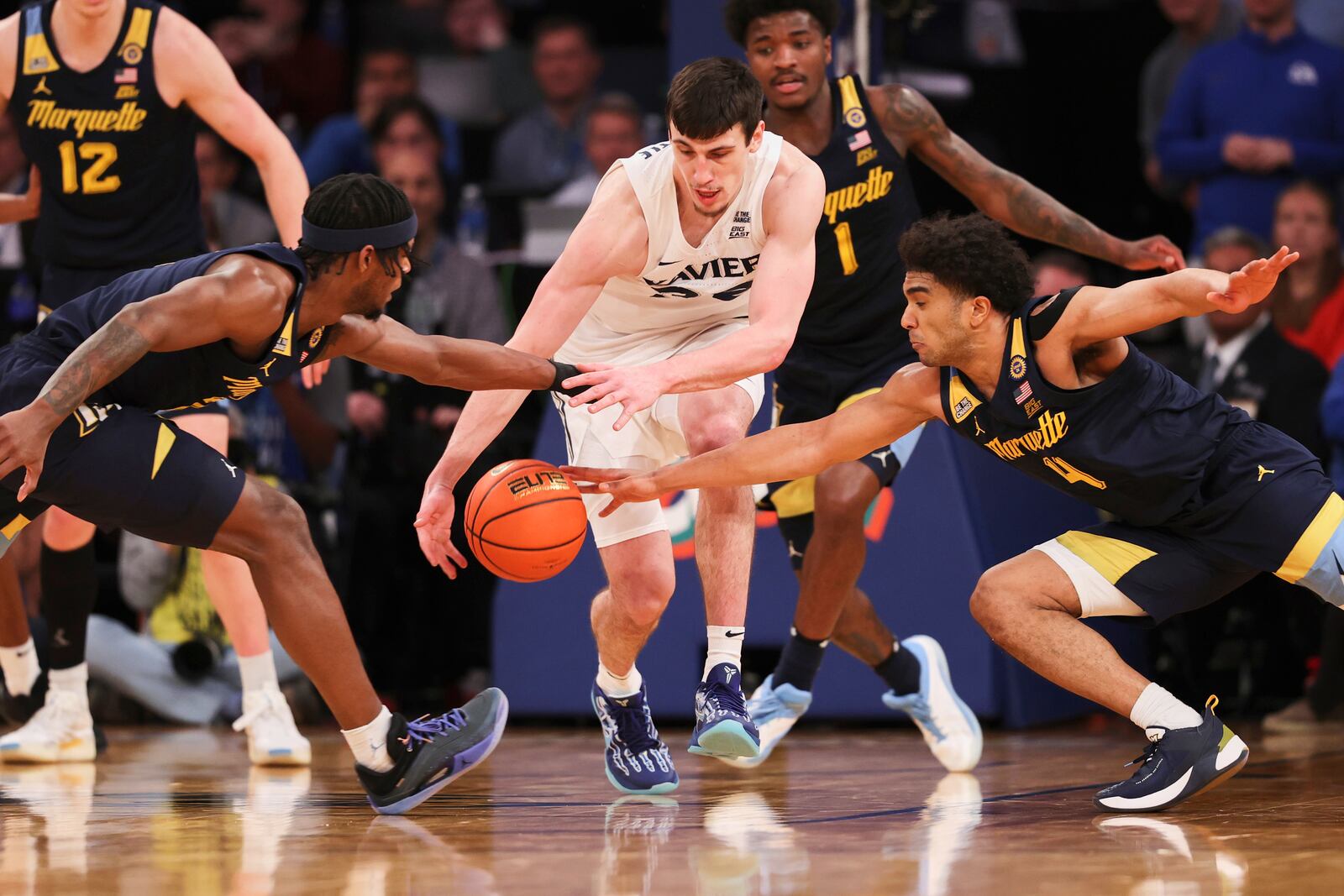 Marquette guards Chase Ross, left, and Stevie Mitchell, right, reach in to try and steal the ball from Xavier forward Zach Freemantle, center, during the second half of an NCAA college basketball game in the quarterfinals of the Big East Conference tournament, Thursday, March 13, 2025, in New York. (AP Photo/Pamela Smith)