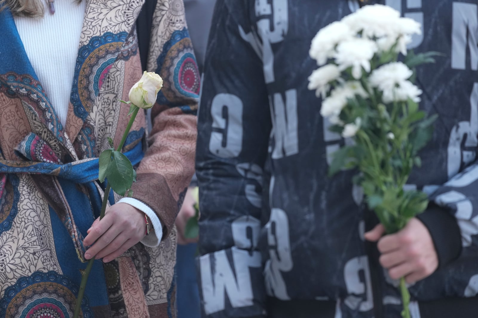 Students hold white flowers in front of the court building during a verdict in trial of parents of a boy who killed 9 students and security guard in school shooting in 2023, in Belgrade, Serbia, Monday, Dec. 30, 2024. (AP Photo/Darko Vojinovic)