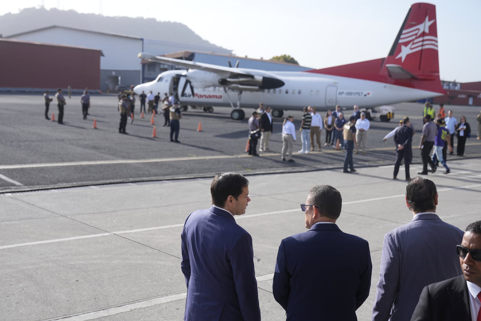 Secretary of State Marco Rubio, left, Frank Alexis Abrego, Panama's Minister of Public Security, center, and Panama's Foreign Minister Javier Martinez-Acha, watch as people board a repatriation flight bound for Colombia at Albrook Airport in Panama City, Monday, Feb. 3, 2025. (AP Photo/Mark Schiefelbein, Pool)