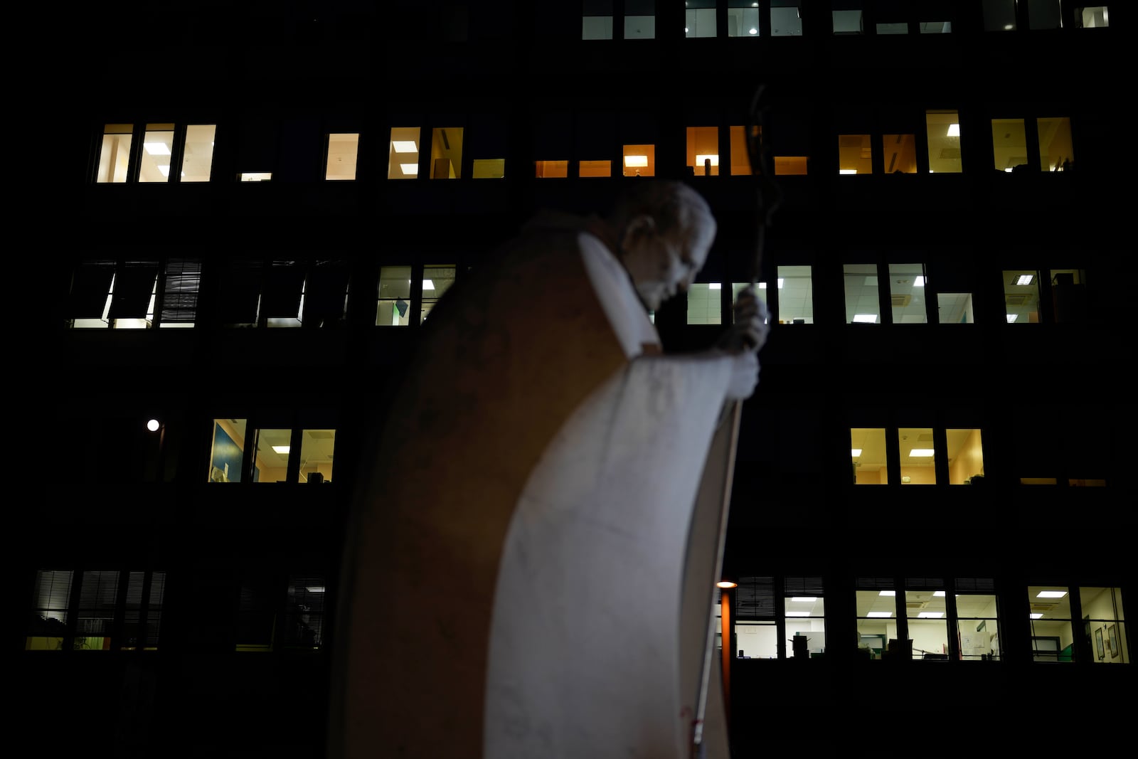 A marble statue of late Pope John Paul II is backdropped by the Agostino Gemelli Polyclinic in Rome, Monday, Feb. 17, 2025, where Pope Francis was hospitalized Friday, Feb. 14, after a weeklong bout of bronchitis worsened and is receiving drug therapy for a respiratory tract infection. (AP Photo/Gregorio Borgia)