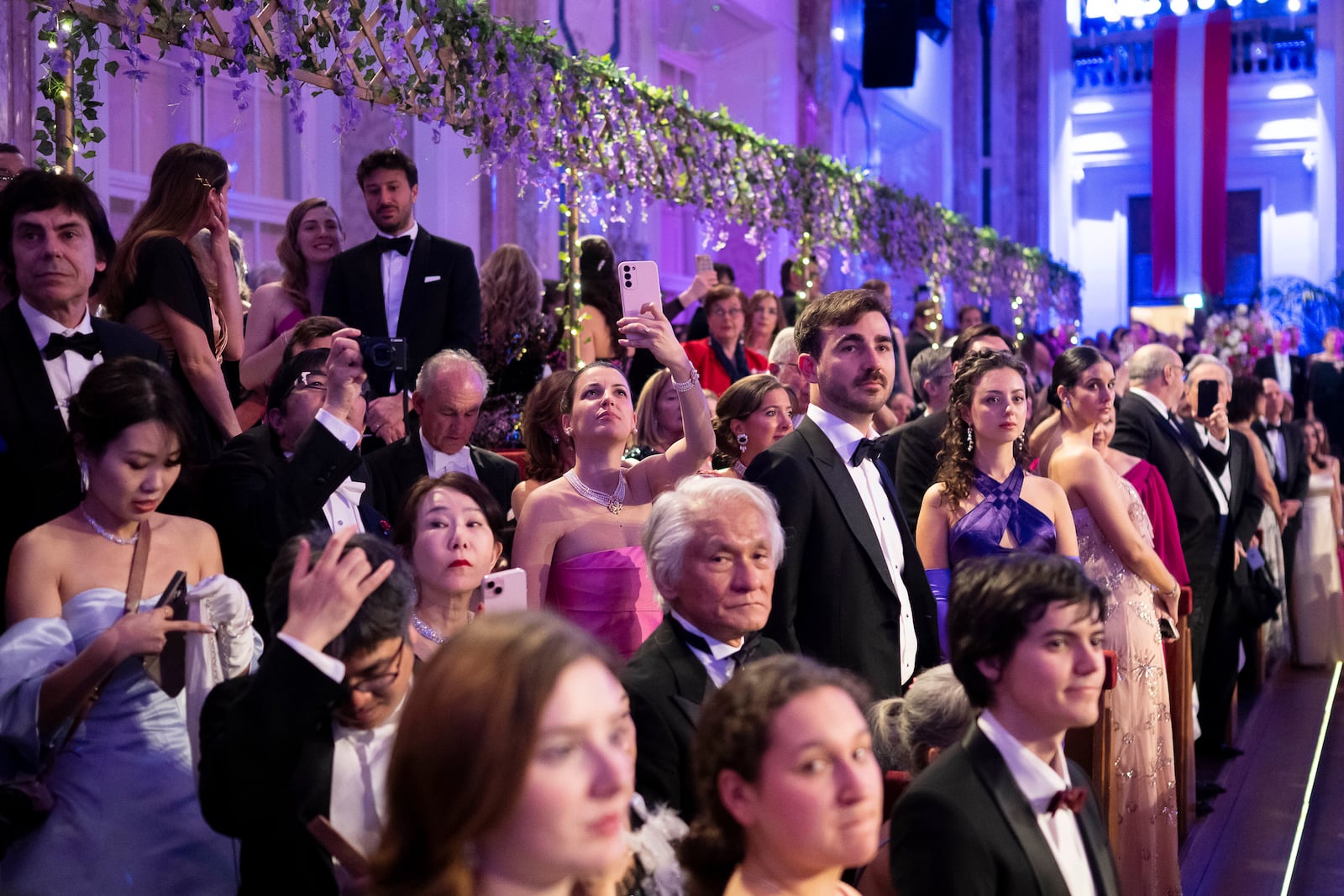 People watch and take pictures during the opening ceremony of the Lawyers' Ball in Vienna, Austria, Saturday, March 1, 2025. (AP Photo/Denes Erdos)