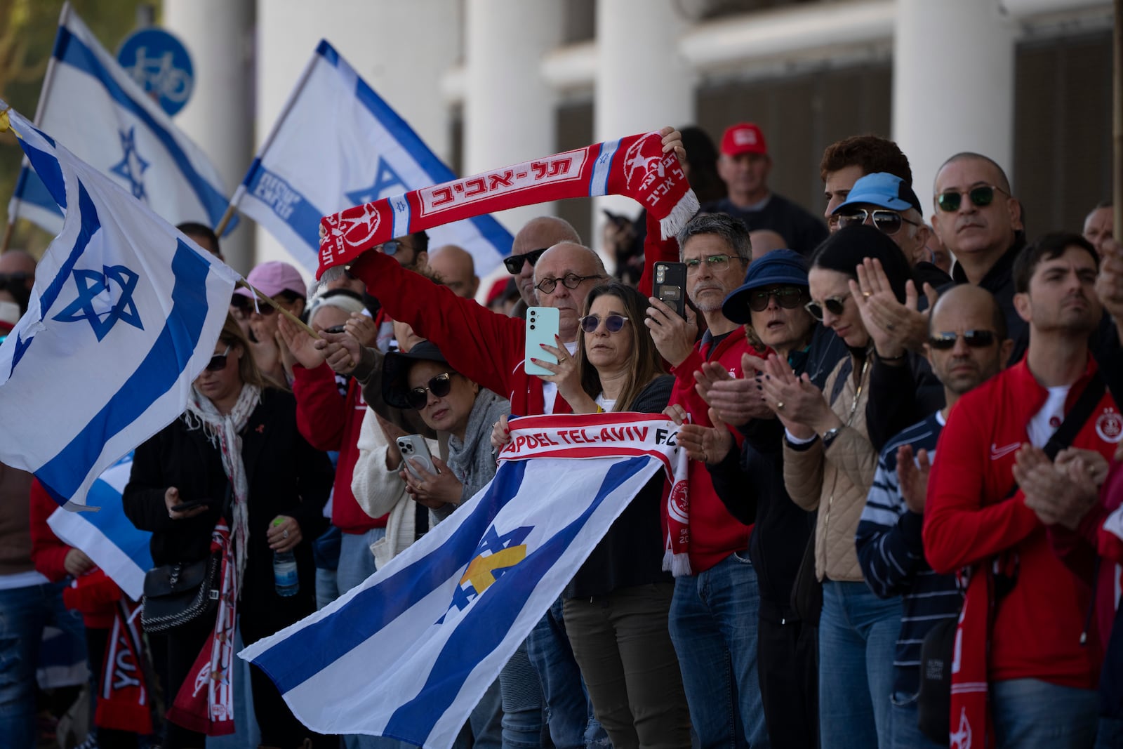 People attend a public memorial ceremony for slain hostage Tsachi Idan, a fan of Hapoel Tel Aviv F.C., who was killed in Hamas captivity in the Gaza Strip, outside the Bloomfield Stadium in Tel Aviv, Israel, Friday, Feb. 28, 2025. (AP Photo/Leo Correa)