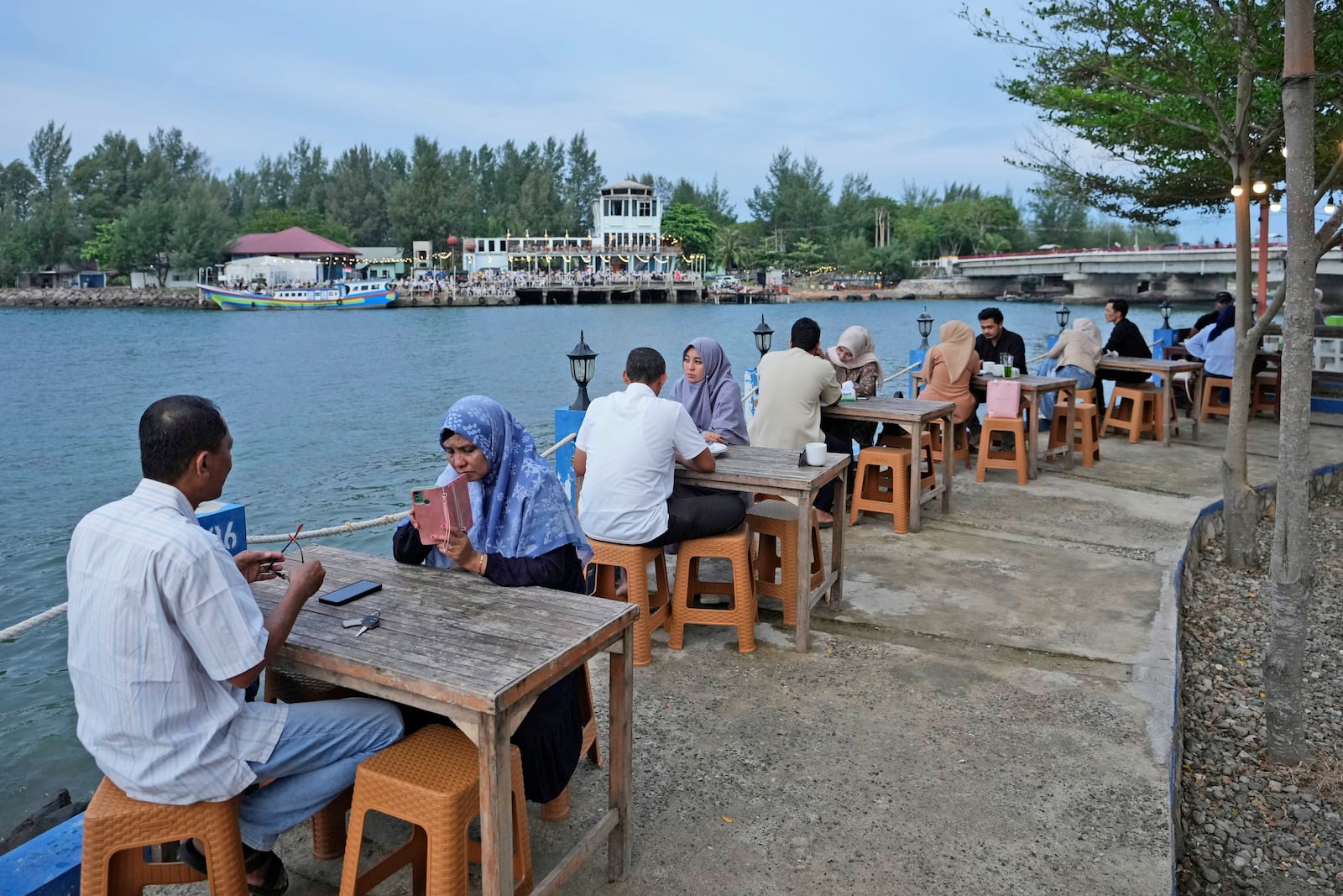 People sit at a cafe on the waterfront near Ulhee Lheue beach, one of the areas hardest his by the Indian Ocean tsunami in 2004, in Banda Aceh, Indonesia, Saturday, Dec 14, 2024. (AP Photo/Achmad Ibrahim)