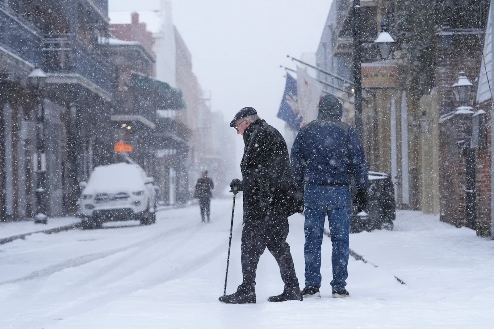 People walk in the French Quarter as snow falls in New Orleans, Tuesday, Jan. 21, 2025. (AP Photo/Gerald Herbert)