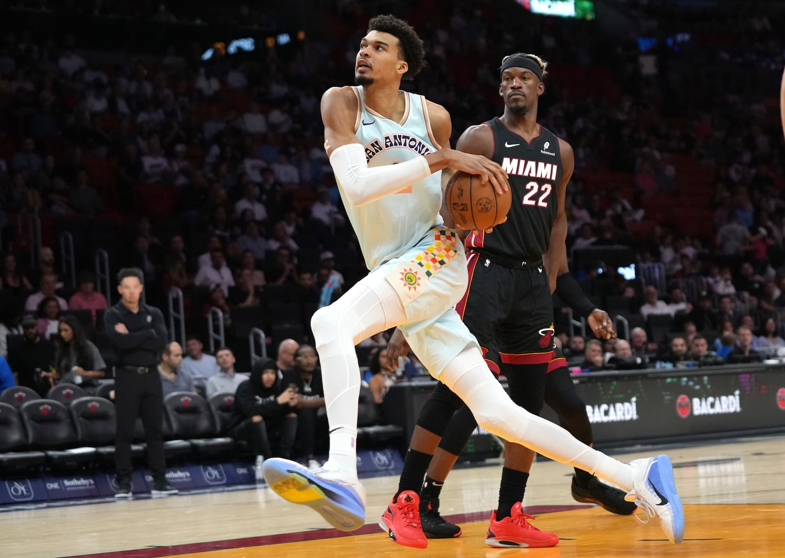 San Antonio Spurs center Victor Wembanyama, left, drives to the basket past Miami Heat forward Jimmy Butler (22) during the second half of an NBA basketball game, Sunday, Jan. 19, 2025, in Miami. (AP Photo/Lynne Sladky)