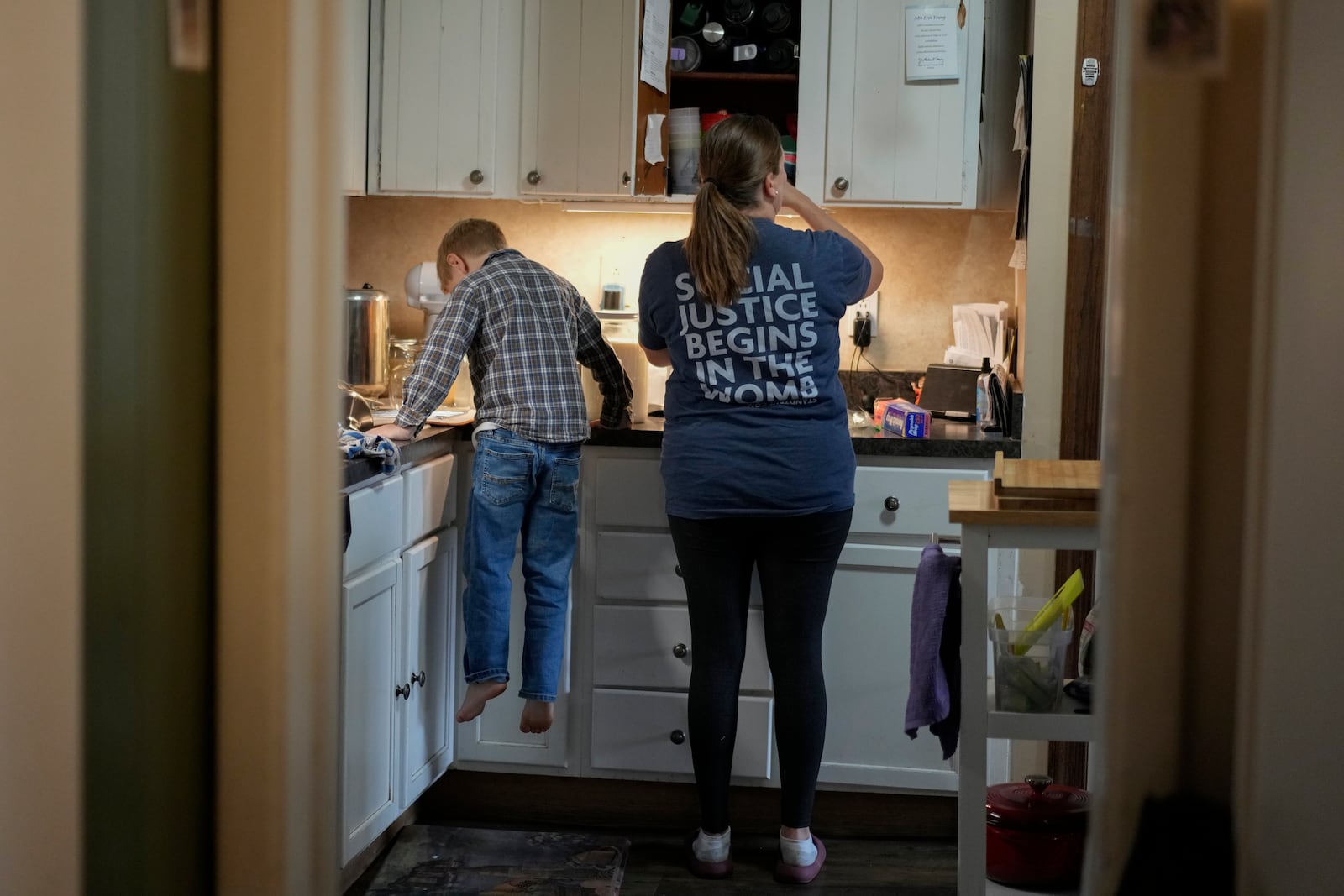 Erin Young wears a T-shirt that reads "Social Justice Begins in the Womb" as she works in the kitchen with her adopted son Isaac, 5, on Tuesday, Nov. 12, 2024, in Sunbury, Ohio. (AP Photo/Carolyn Kaster)