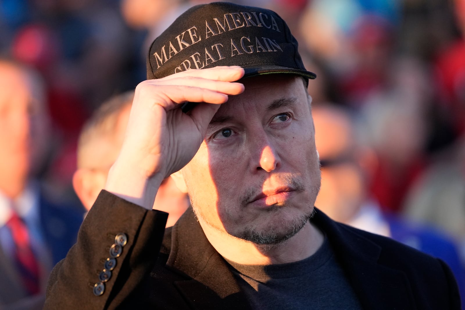 FILE - Elon Musk listens as Republican presidential nominee former President Donald Trump speaks at a campaign event at the Butler Farm Show on Oct. 5, 2024, in Butler, Pa. (AP Photo/Alex Brandon, File)