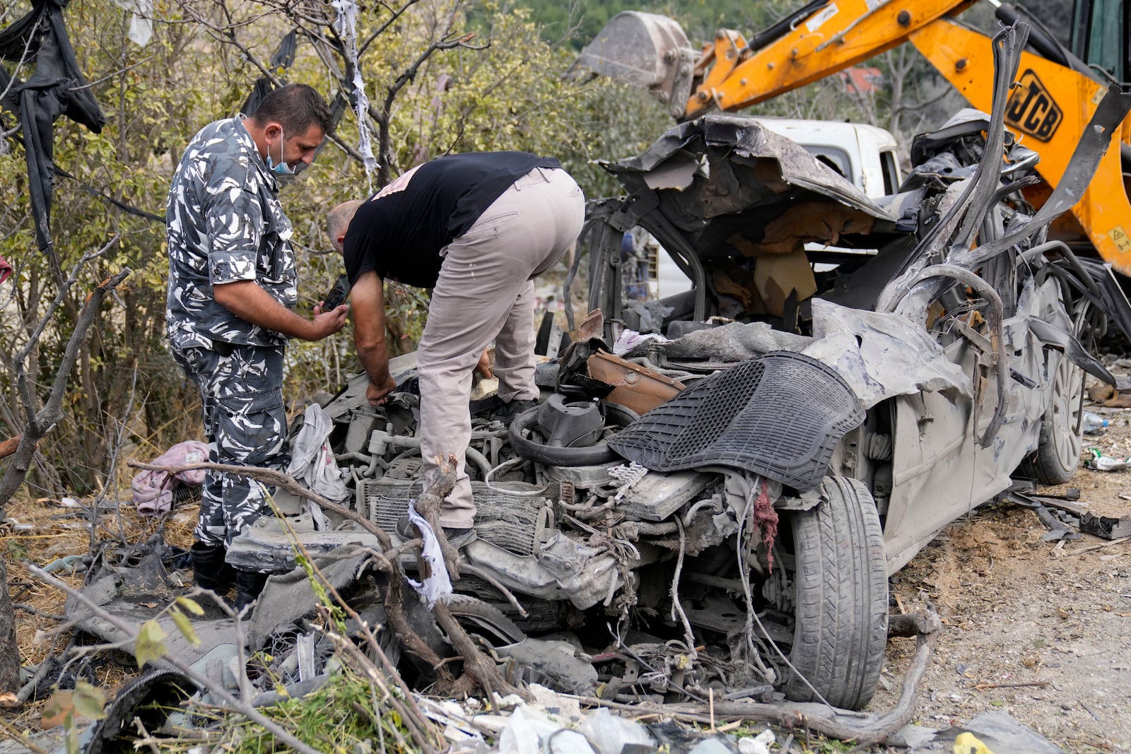 Lebanese policemen check a destroyed car at the site of Monday's Israeli airstrike in Aito village, north Lebanon, Tuesday, Oct. 15, 2024. (AP Photo/Hussein Malla)