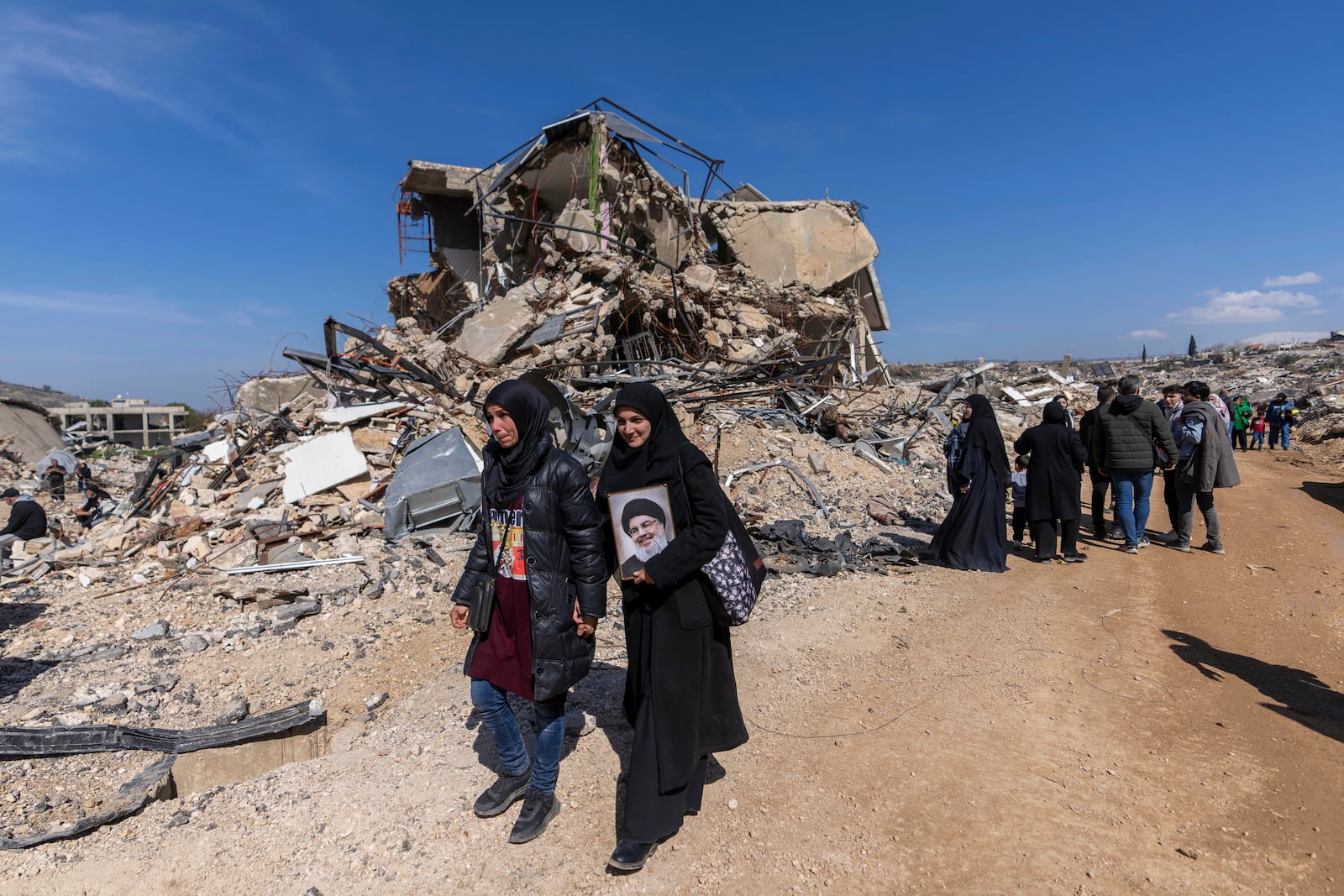 Lebanese citizens check the destruction in their village caused by the Israeli air and ground offensive, in the town of Kfar Kila, southern Lebanon, Tuesday, Feb. 18, 2025. (AP Photo/Hassan Ammar)