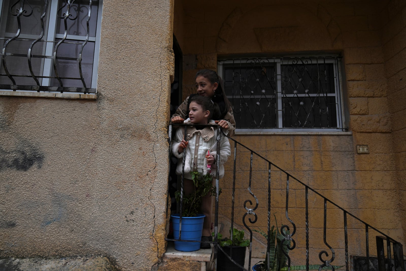 Palestinian girls watch the funeral of Zein Atatrah, 18, as they stand on the steps of their house, in the West Bank town of Ya'bad Friday, Dec. 27, 2024. (AP Photo/Nasser Nasser)