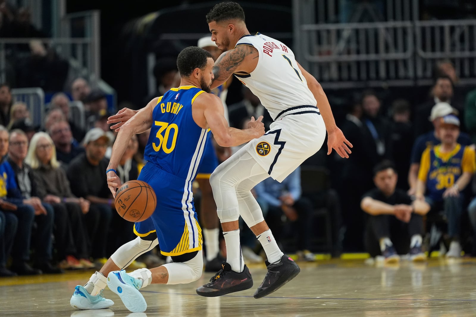 Golden State Warriors guard Stephen Curry (30) moves the ball while defended by Denver Nuggets forward Michael Porter Jr. (1) during the first half of an NBA basketball game Monday, March 17, 2025, in San Francisco. (AP Photo/Godofredo A. Vásquez)