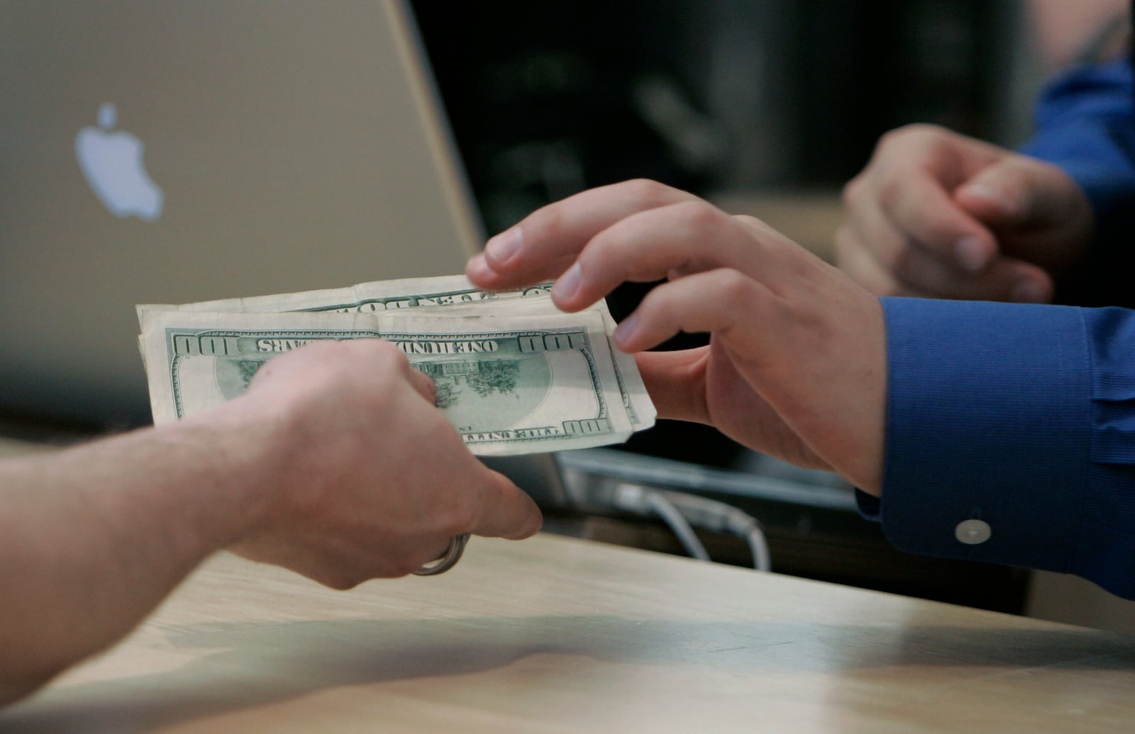 A customer hands over hundreds of dollars at the Apple Store in downtown Chicago, Friday, June 29, 2007, to purchase the company's new iPhone, a gadget that combines the functions of a cell phone, iPod media player and wireless Web browser.  Apple is banking on the new do-everything phone with a touch-sensitive screen to become its third core business next to its moneymaking iPod players and Macintosh computers. (AP Photo/M. Spencer Green)