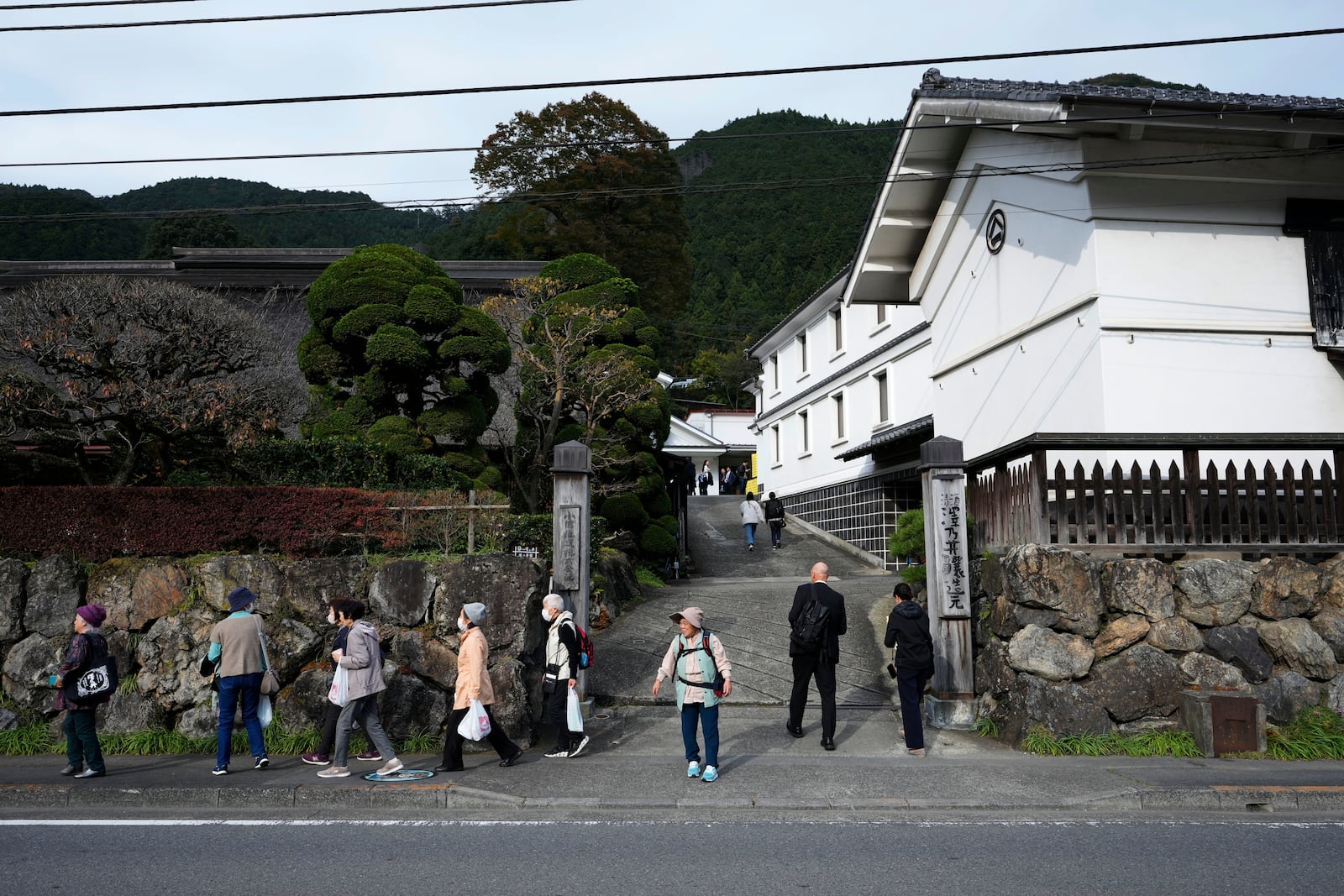 Visitors of Ozawa Sake Brewery leave as journalists enter the brewery on a media tour in Ome, on the western outskirts of Tokyo, Japan, Wednesday, Nov. 13, 2024. (AP Photo/Hiro Komae)