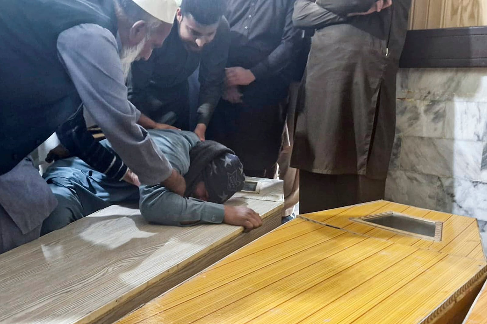 A Pakistani mourns next to the caskets of the victims of bomb explosion in a mosque within a pro-Taliban seminary, at a hospital in Nowshera, a town in the Pakistan's northwestern Khyber Pakhtunkhwa province, Friday, Feb. 28, 2025. (AP Photo/Riaz Khan)