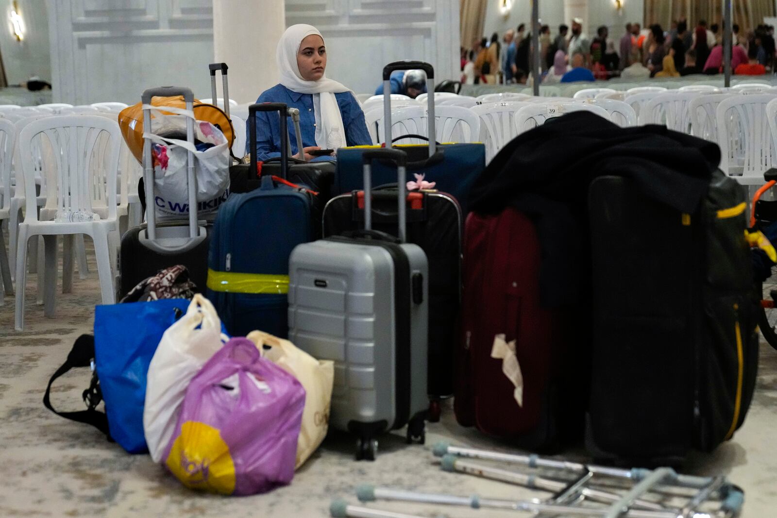 A Turkish citizen sits next of her belongings, as she waits to board a Turkish navy vessel to be evacuated to Turkey at a gathering point, in Beirut, Lebanon, Wednesday, Oct. 9, 2024. (AP Photo/Hussein Malla)