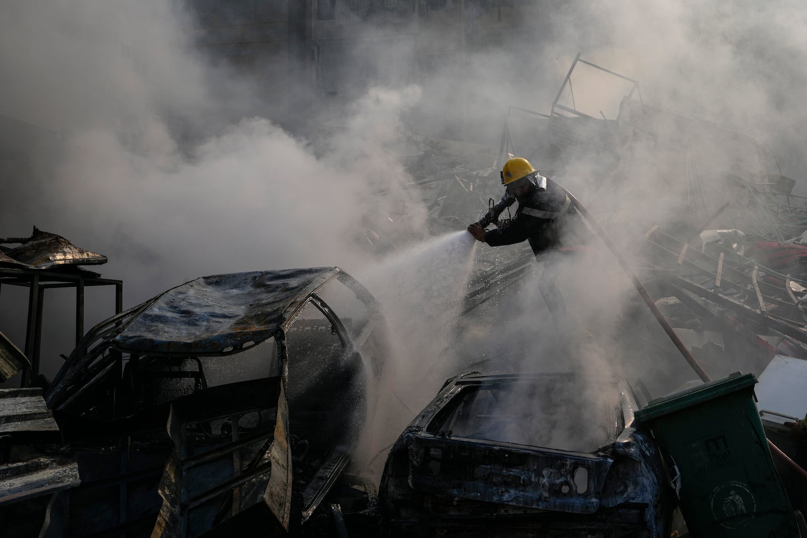 A civil defense worker extinguishes a fire as smoke rises from the site of an Israeli airstrike in Dahiyeh, Beirut, Lebanon, Friday, Nov. 1, 2024. (AP Photo/Hassan Ammar)