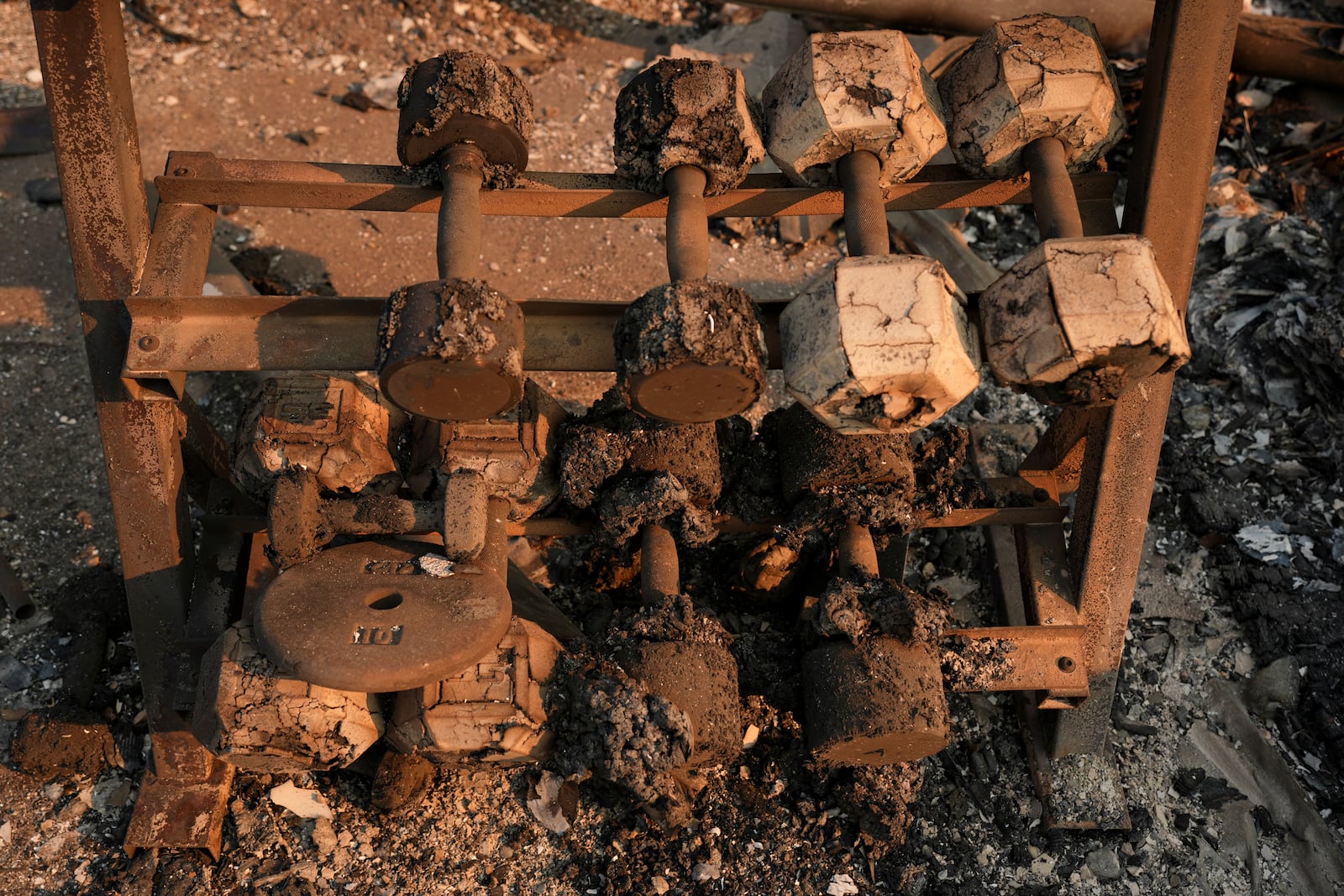 A charred set of weights is shown in a fire-ravaged property in the aftermath of the Eaton Fire Friday, Jan. 10, 2025 in Altadena, Calif. (AP Photo/Jae C. Hong)