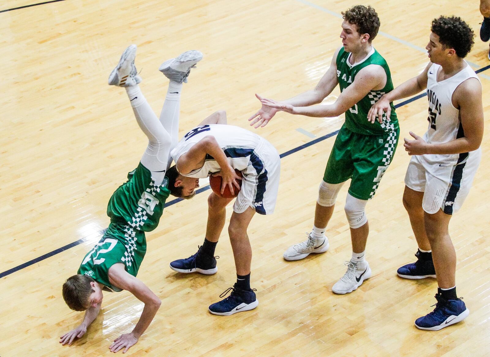 Badin’s Josh Hegemann dives over the back of Edgewood’s Caleb Allen during Friday night’s game at Ron Kash Court in St. Clair Township. Badin won 49-46. NICK GRAHAM/STAFF