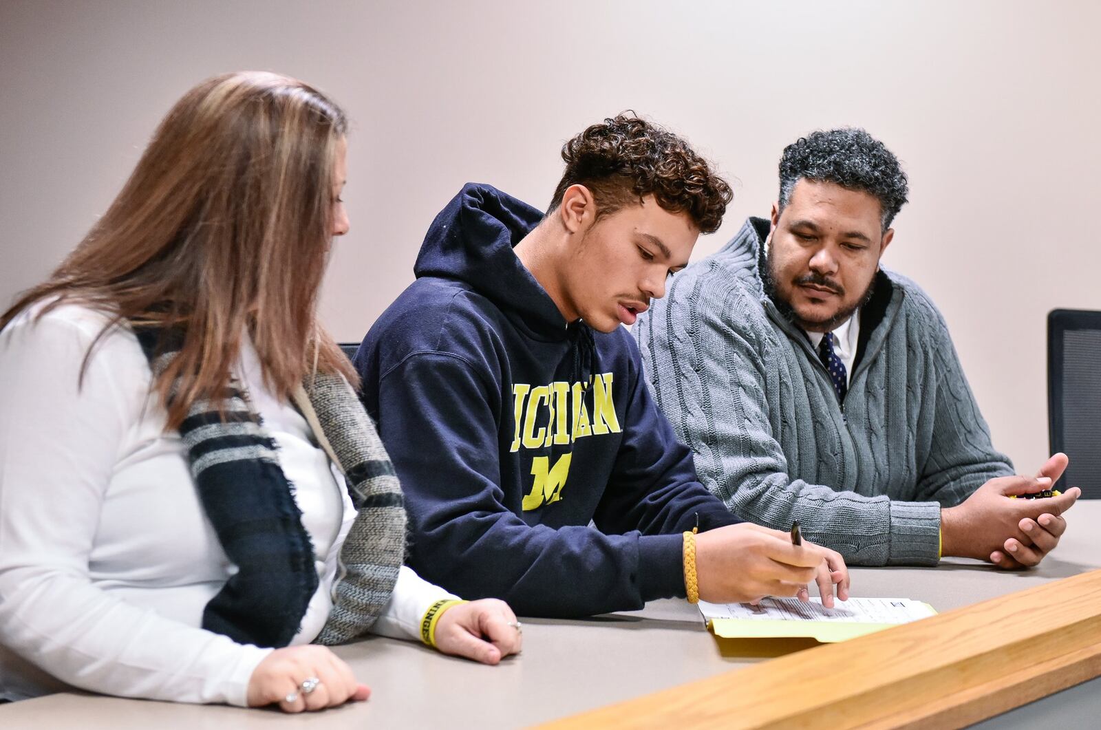 Fairfield senior Erick All (middle) sits with his parents Kelly and Erick All during an early National Signing Day ceremony Wednesday morning at Fairfield High School. All signed with the University of Michigan. NICK GRAHAM/STAFF