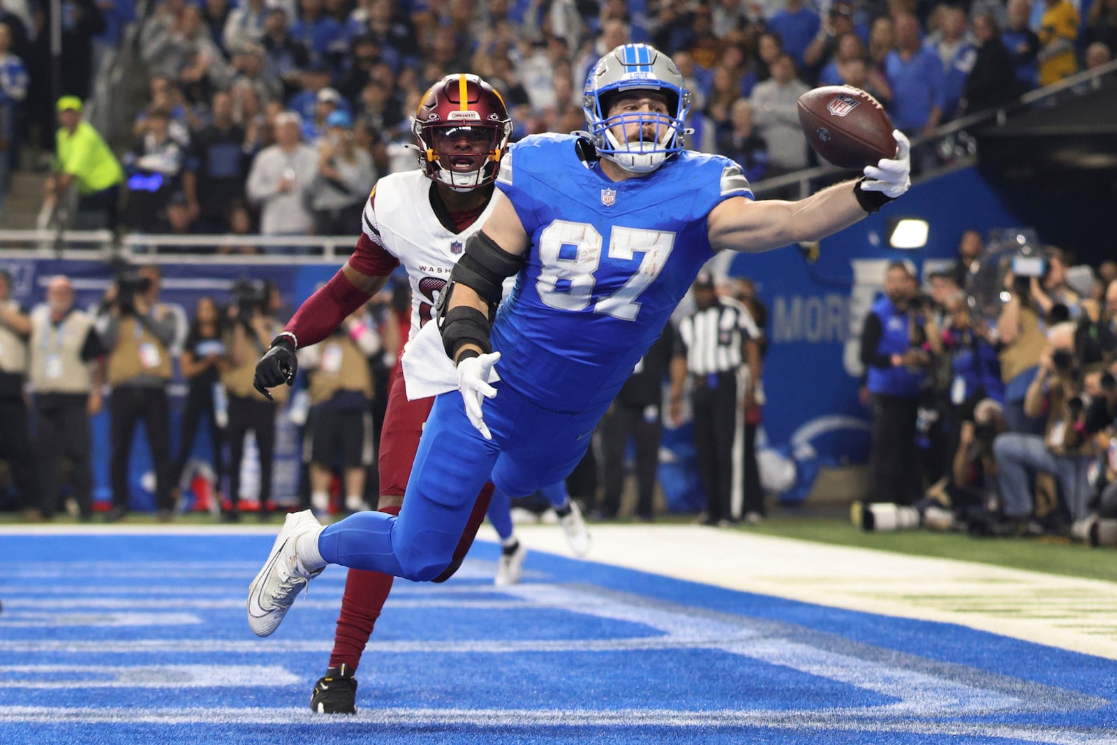 Detroit Lions tight end Sam LaPorta (87) catches a two-yard touchdown pass as Washington Commanders safety Percy Butler (35) defends during the first half of an NFL football divisional playoff game, Saturday, Jan. 18, 2025, in Detroit. (AP Photo/Mike Mulholland)