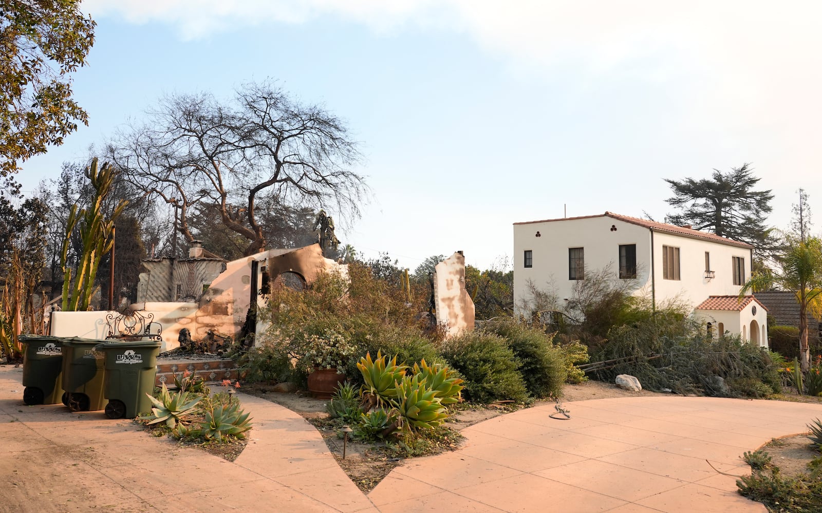 A home at left destroyed by the Eaton Fire stands next to an intact residence, Thursday, Jan. 9, 2025, in Altadena, Calif. (AP Photo/Chris Pizzello)