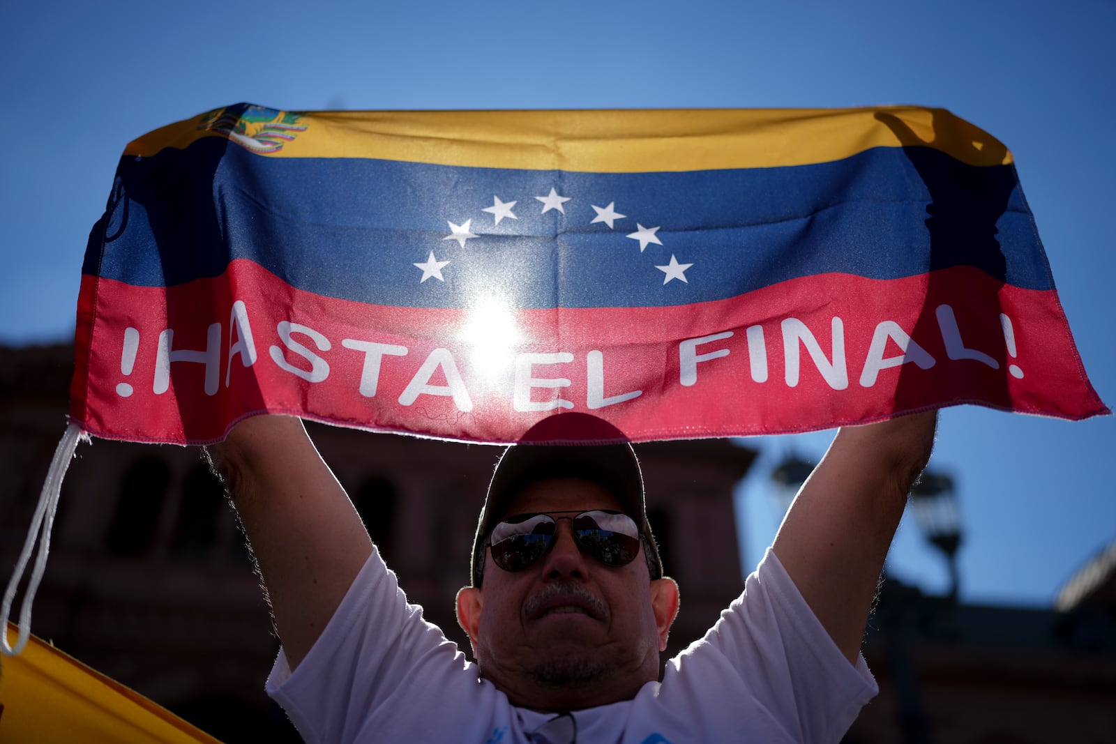 Leo Zambrano, supporter of Venezuela's opposition leader Edmundo Gonzalez Urrutia, holds a Venezuela's flag at Plaza de Mayo, outside the government house where he meets with Argentine President Javier Milei in Buenos Aires, Argentina, Saturday, Jan. 4, 2025. Gonzalez, who claims he won the 2024 presidential election and is recognized by some countries as the legitimate president-elect, traveled from exile in Madrid to Argentina. (AP Photo/Natacha Pisarenko)