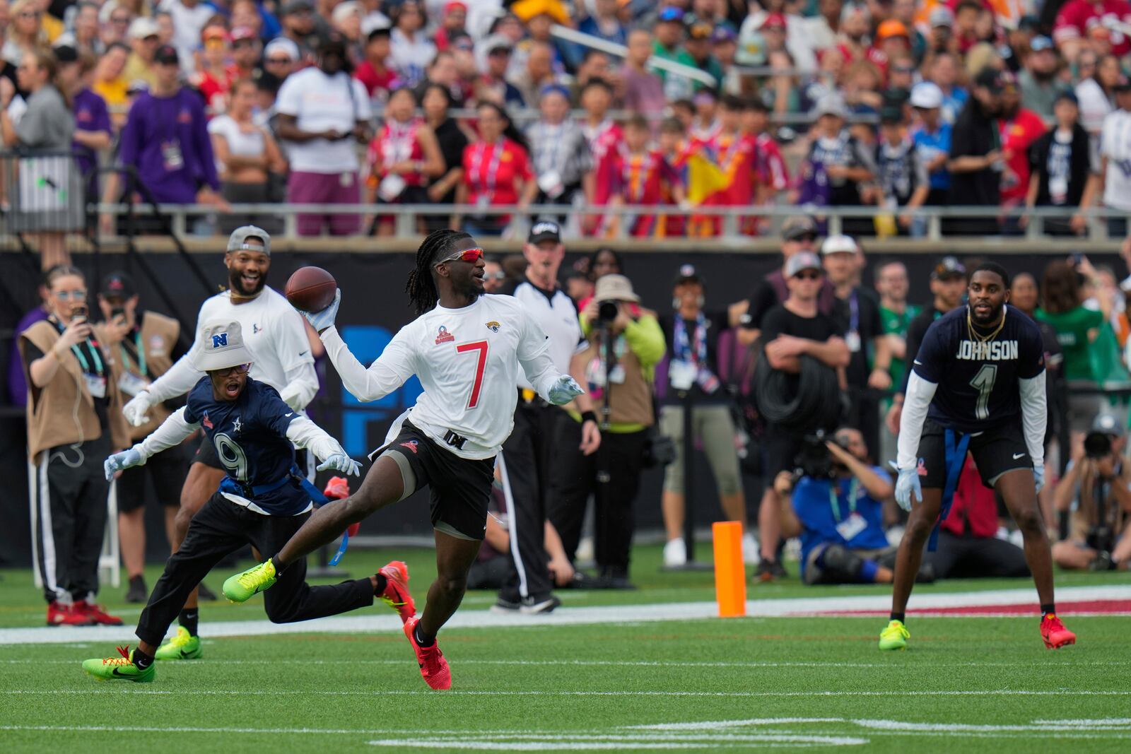 AFC wide receiver Brian Thomas Jr. (7), of the Jacksonville Jaguars, evades NFC return specialist KaVontae Turpin (9), of the Dallas Cowboys, as he throws a lateral pass during the flag football event at the NFL Pro Bowl, Sunday, Feb. 2, 2025, in Orlando. (AP Photo/Chris O'Meara)