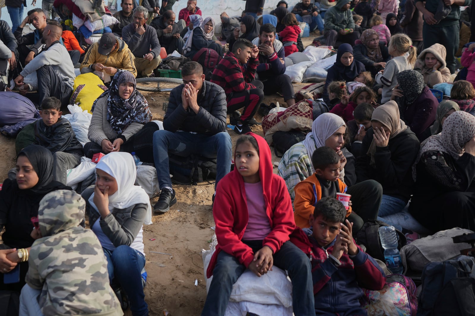 Palestinians wait next to their belongings in central Gaza, Saturday, Jan. 25, 2025, as the Israeli military is warning Palestinians not to return to northern Gaza. (AP Photo/Abdel Kareem Hana)